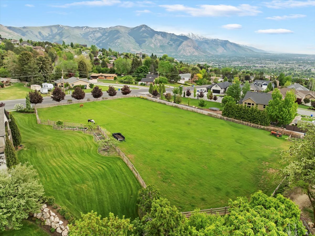Expansive green lot featuring manicured lawns, a fenced perimeter, and established landscaping