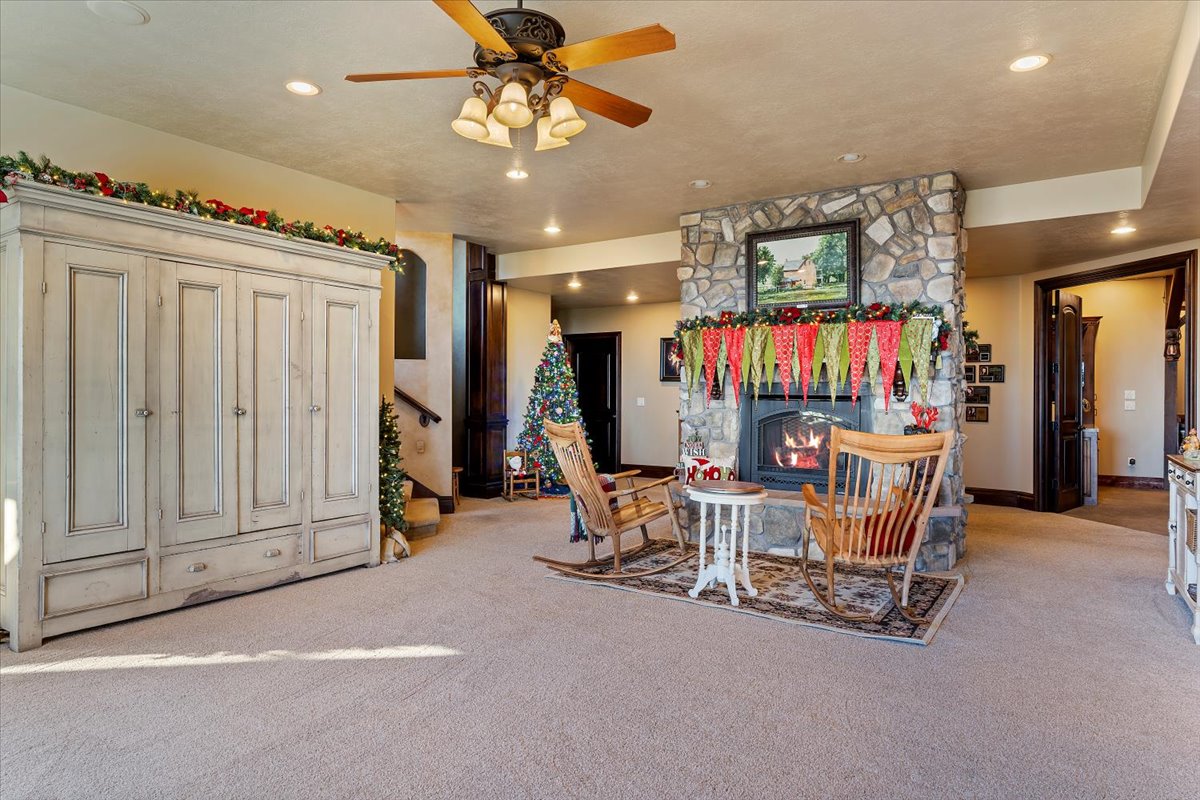 Stone-clad fireplace with a raised hearth, recessed lighting, and a ceiling fan with integrated lighting