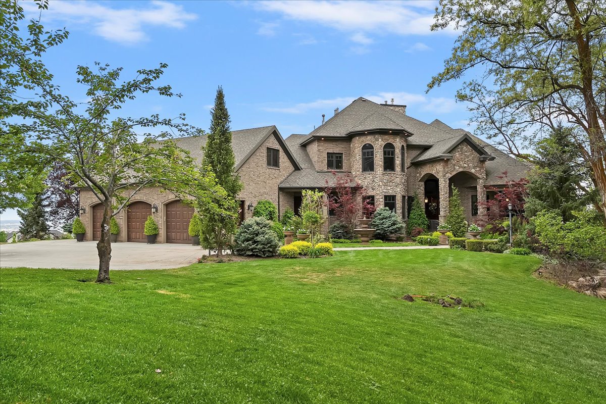 Brick and stone exterior featuring an arched entry, a prominent turret, and a three-car garage with wood-finish doors