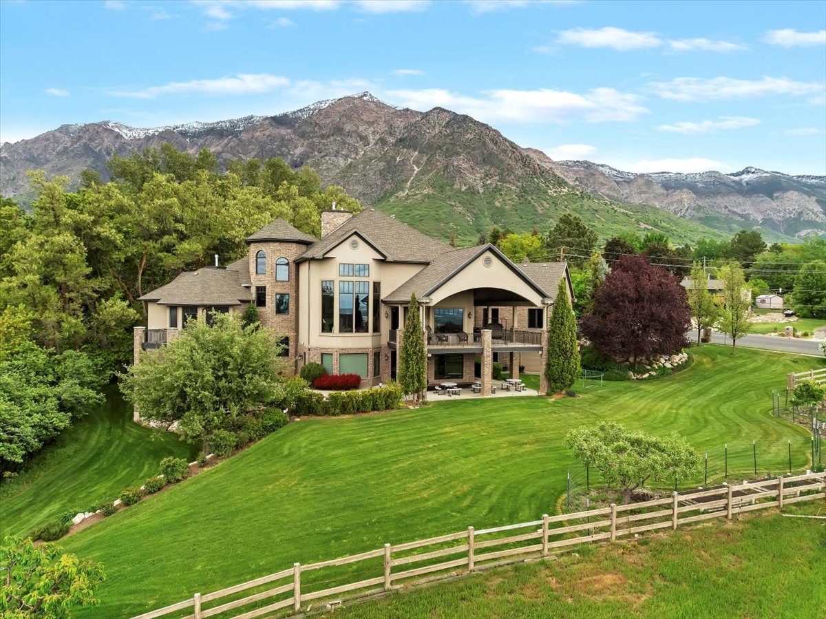 Two-story residence featuring a combination of stone and stucco siding, a multi-level deck, and an expansive lawn