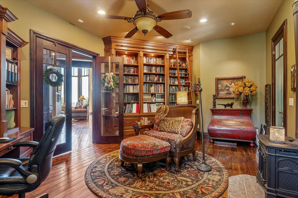 Expansive built-in shelving with rolling ladder, wood-finish flooring, recessed lighting, and a ceiling fan