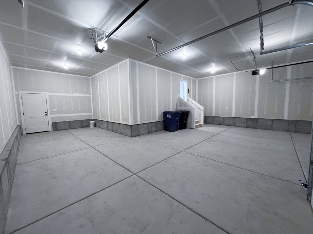 Spacious garage featuring concrete flooring and exposed drywall
