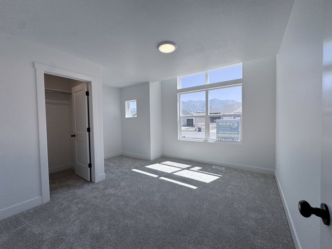 Spacious room featuring gray carpeting, white walls, and a large multi-pane window with transom above