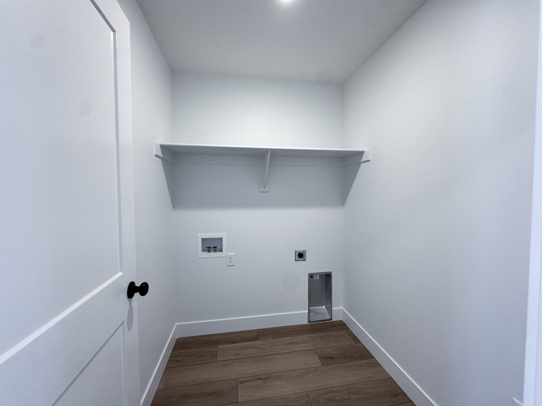 Laundry area featuring wood-finish flooring, white baseboards, a single built-in shelf, and recessed lighting