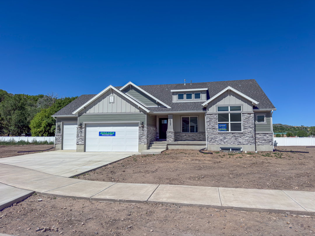 Contemporary residence featuring a stone and siding facade, a prominent entryway, multi-pane windows, a two-car garage, and a concrete driveway