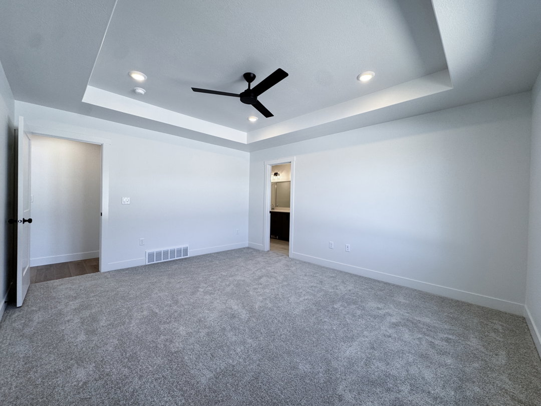 Spacious room featuring gray carpeting, white walls, and a tray ceiling with recessed lighting