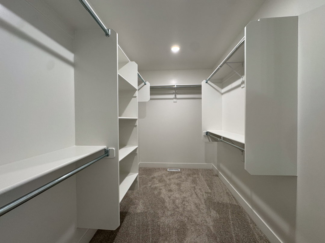 Walk-in closet featuring built-in shelving, multiple hanging rods, recessed lighting, and carpet flooring