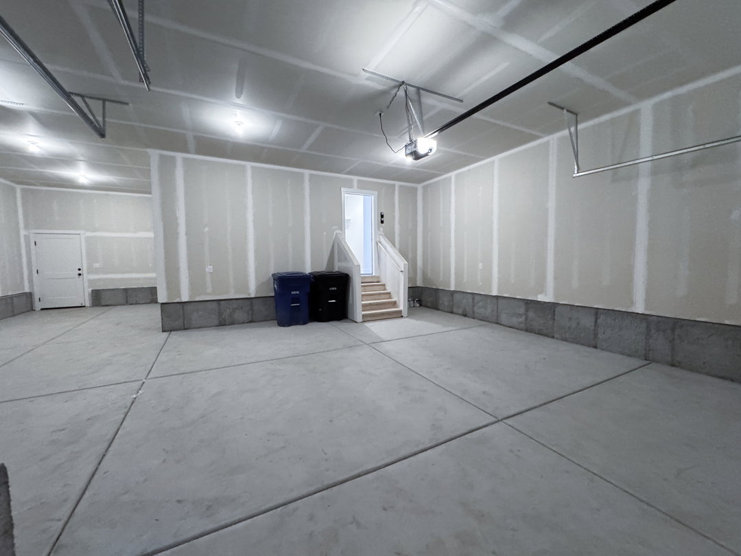 Spacious garage with a concrete floor, exposed drywall, and an automatic garage door opener