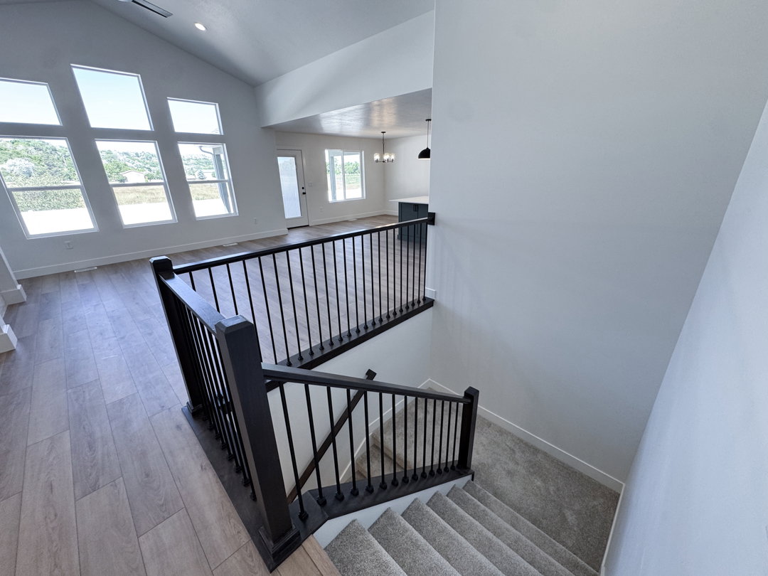 Vaulted ceilings creating an expansive atmosphere with a striking wall of angled windows and light wood-finish flooring