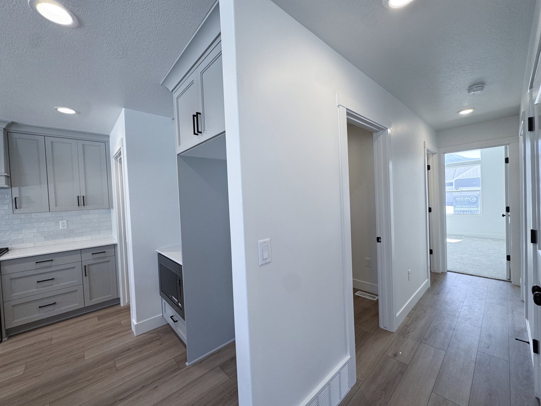 Modern kitchen featuring light gray cabinetry, white subway tile backsplash, and quartz countertops