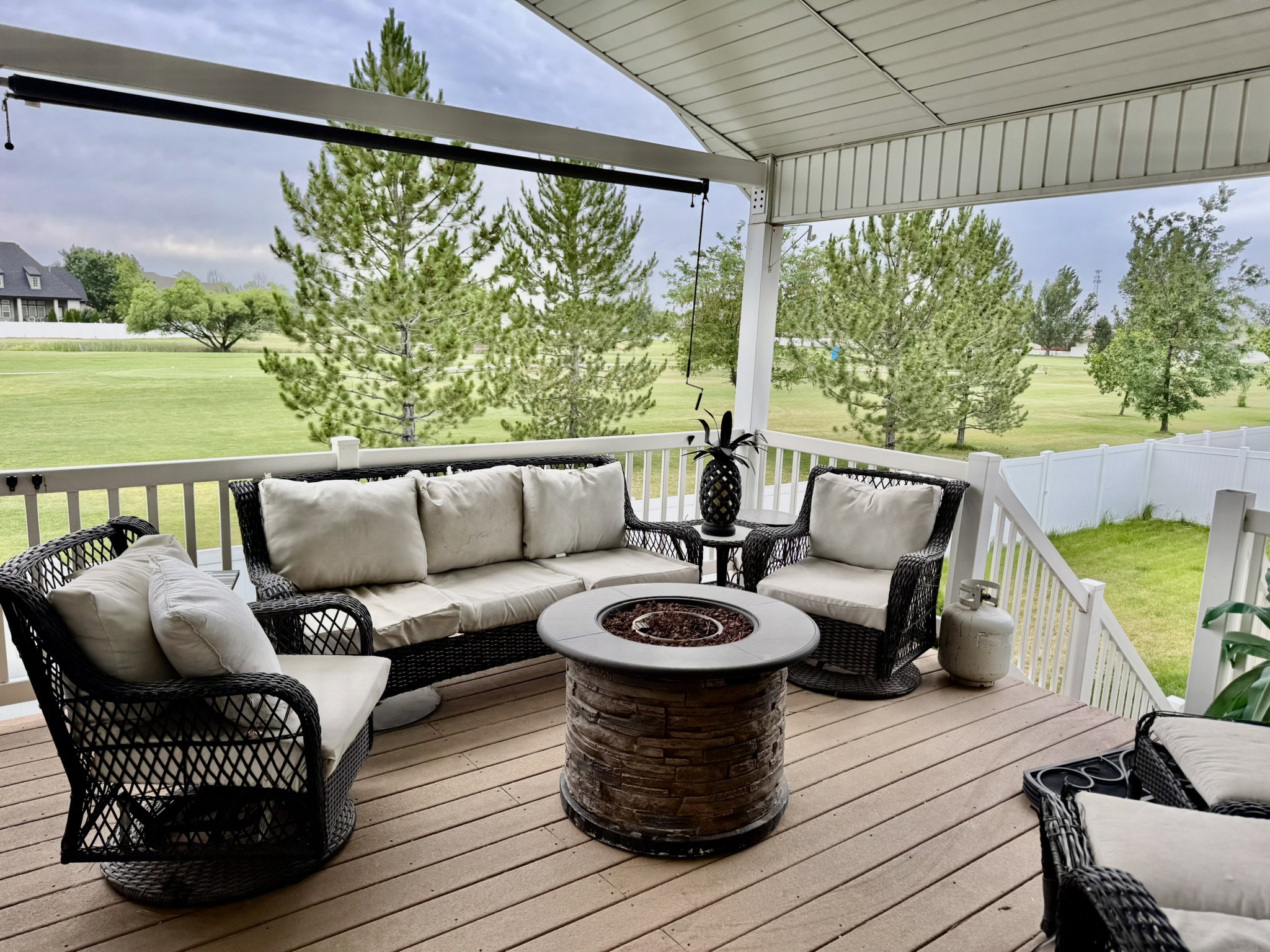 Expansive covered deck featuring wood-finish flooring, a white railing, and a built-in stone-look fire pit