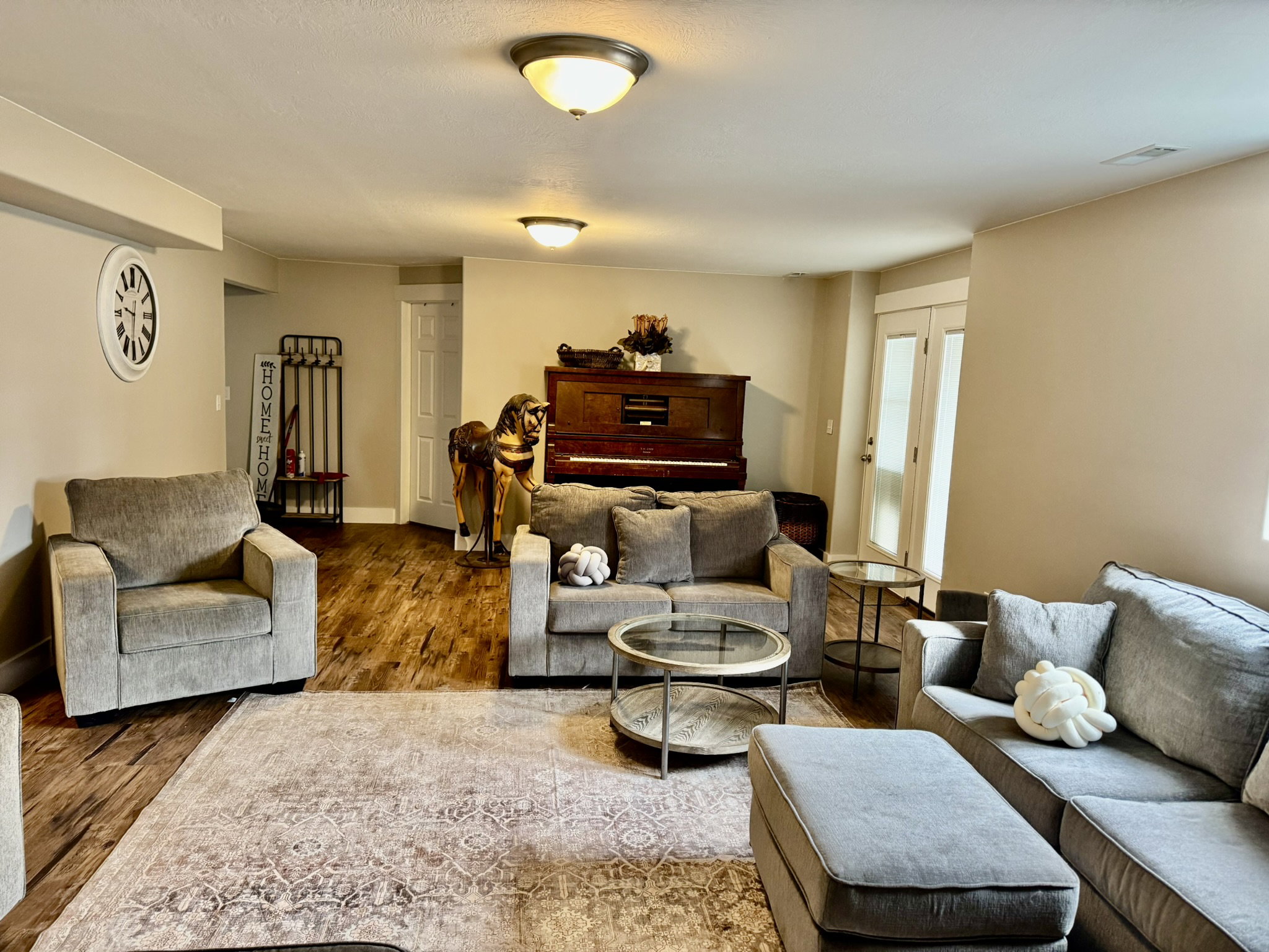 Spacious living area featuring wood-finish flooring, neutral wall tones, recessed lighting, and a white interior door