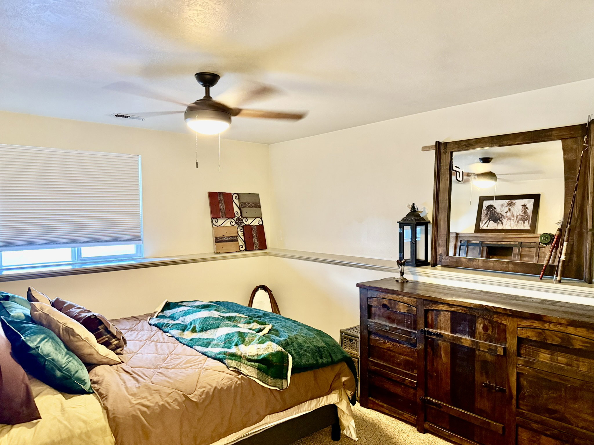 Bedroom featuring plush carpeting, a large window with privacy blinds, and a ceiling fan with integrated lighting