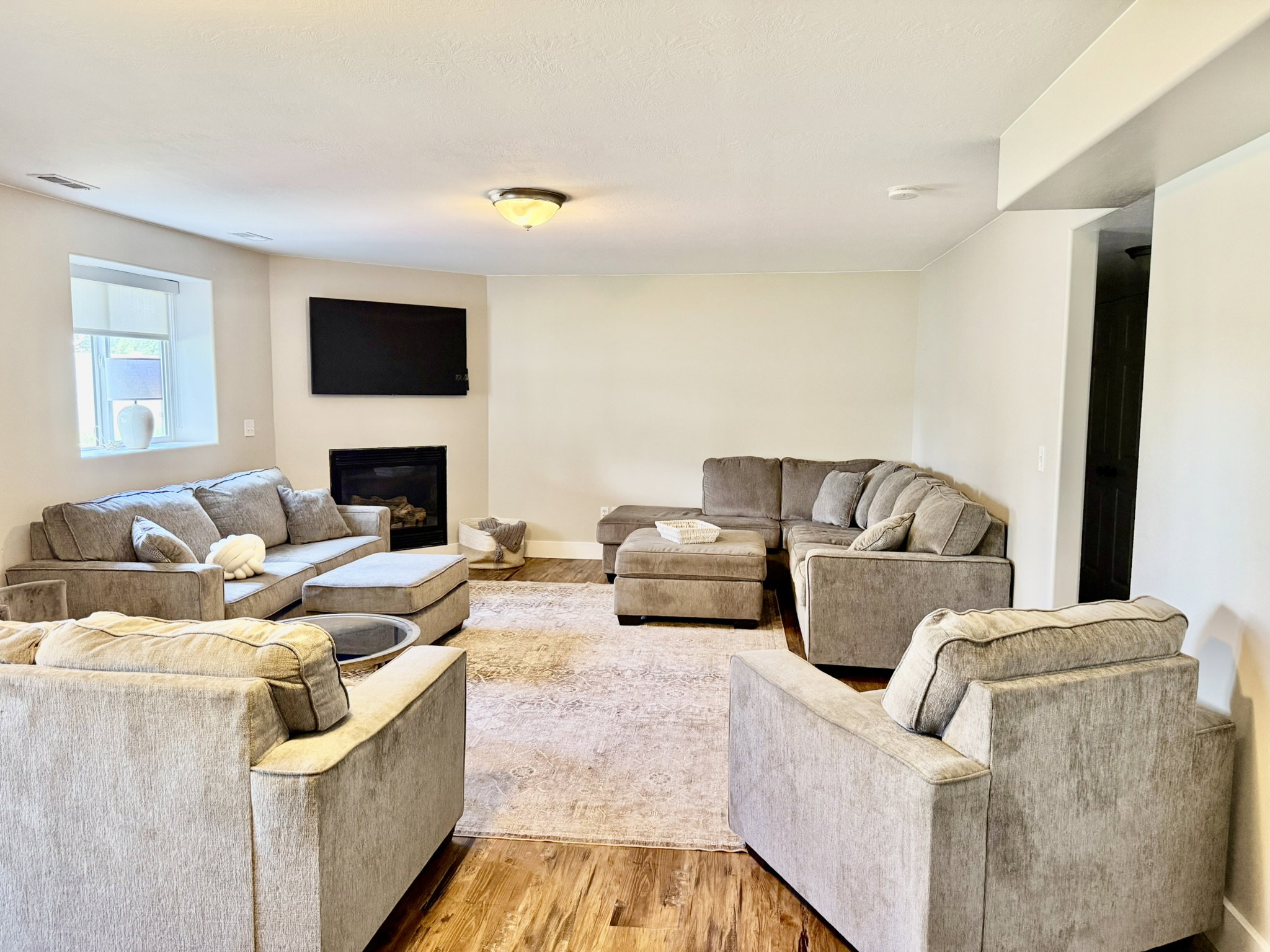Spacious living area featuring wood-finish flooring, a corner fireplace, and a recessed window