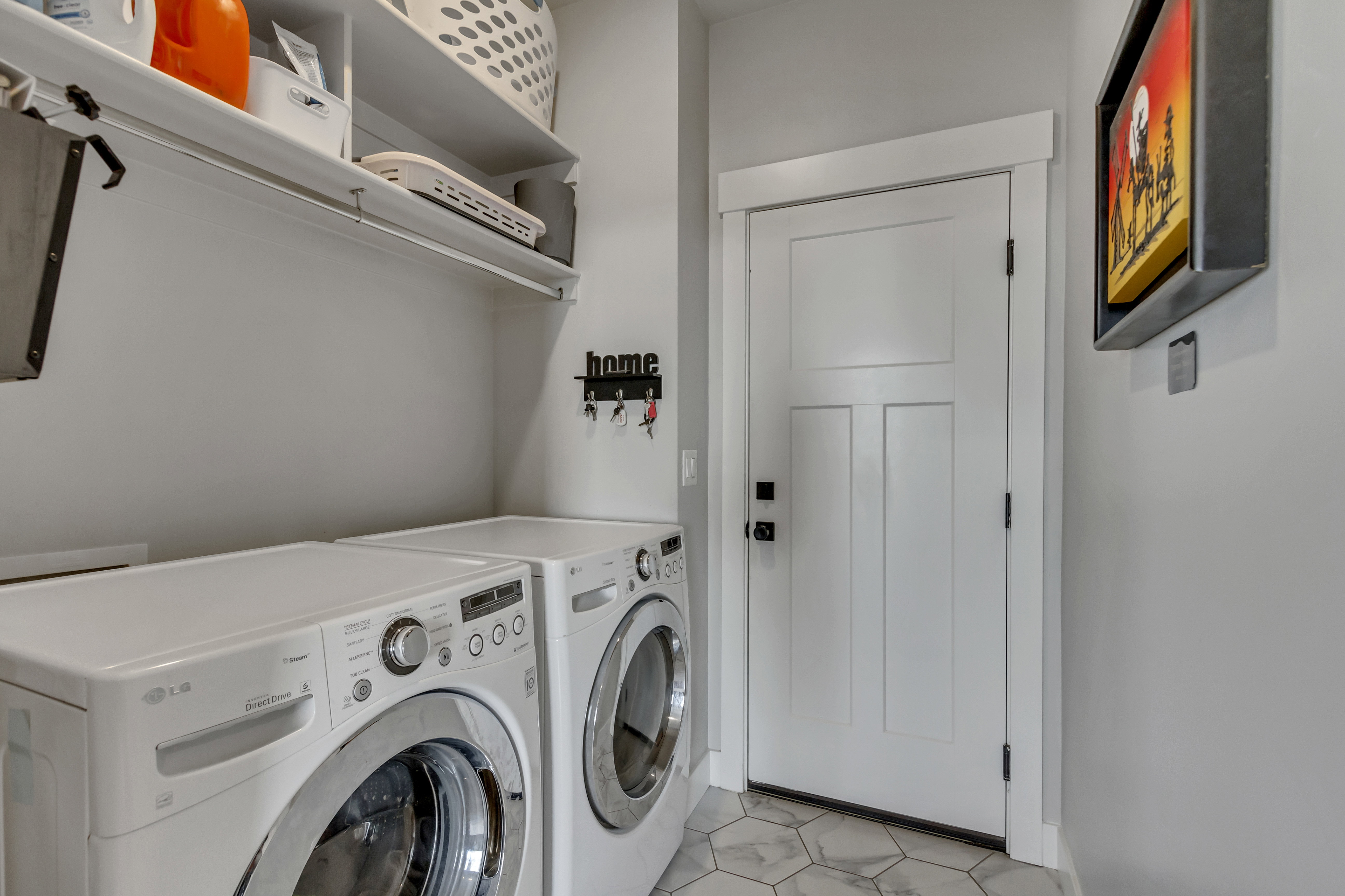 Dedicated laundry area featuring a white paneled door, hexagon tile flooring, and integrated shelving with a hanging rod