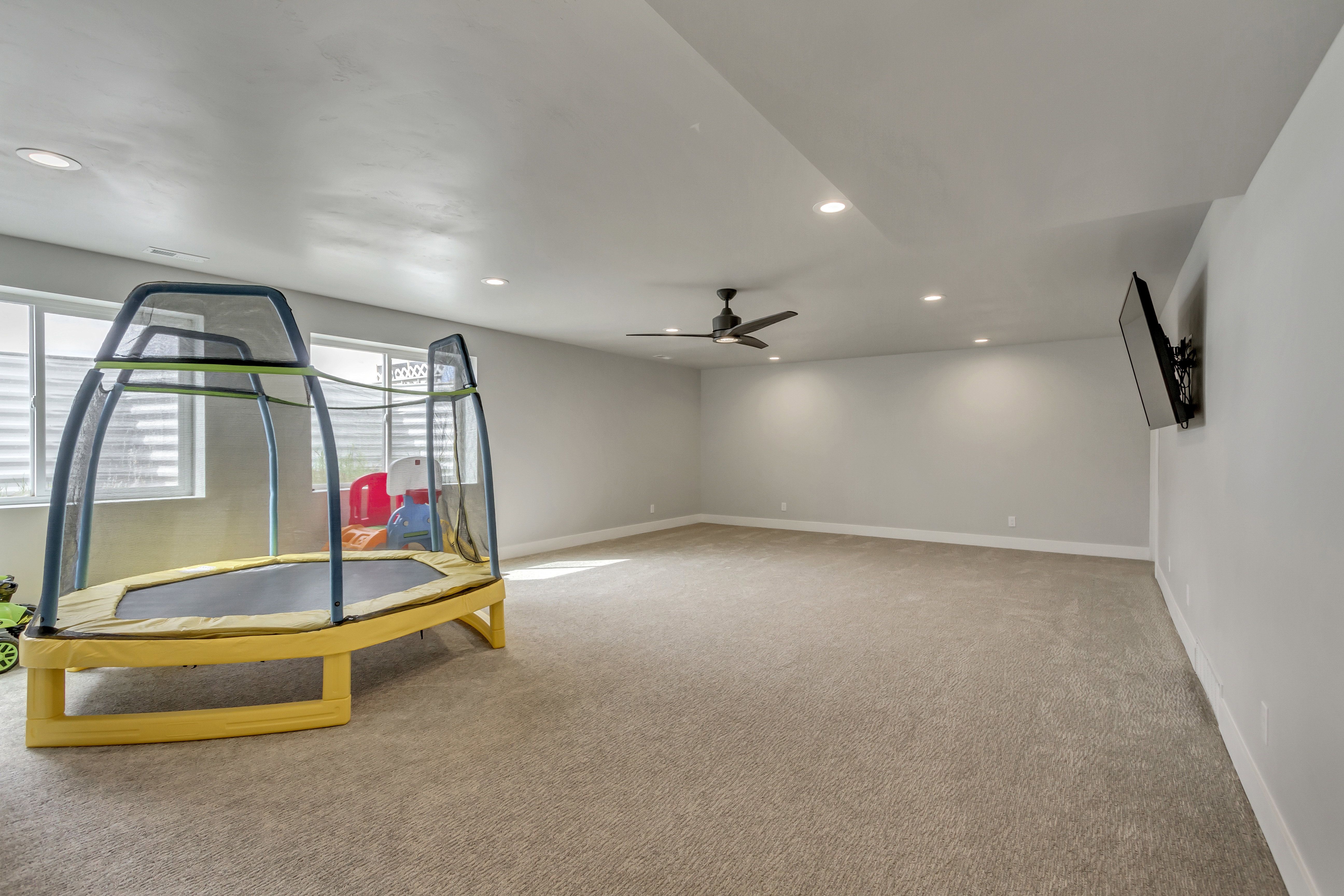 Spacious room featuring neutral carpeting, recessed lighting, and a ceiling fan