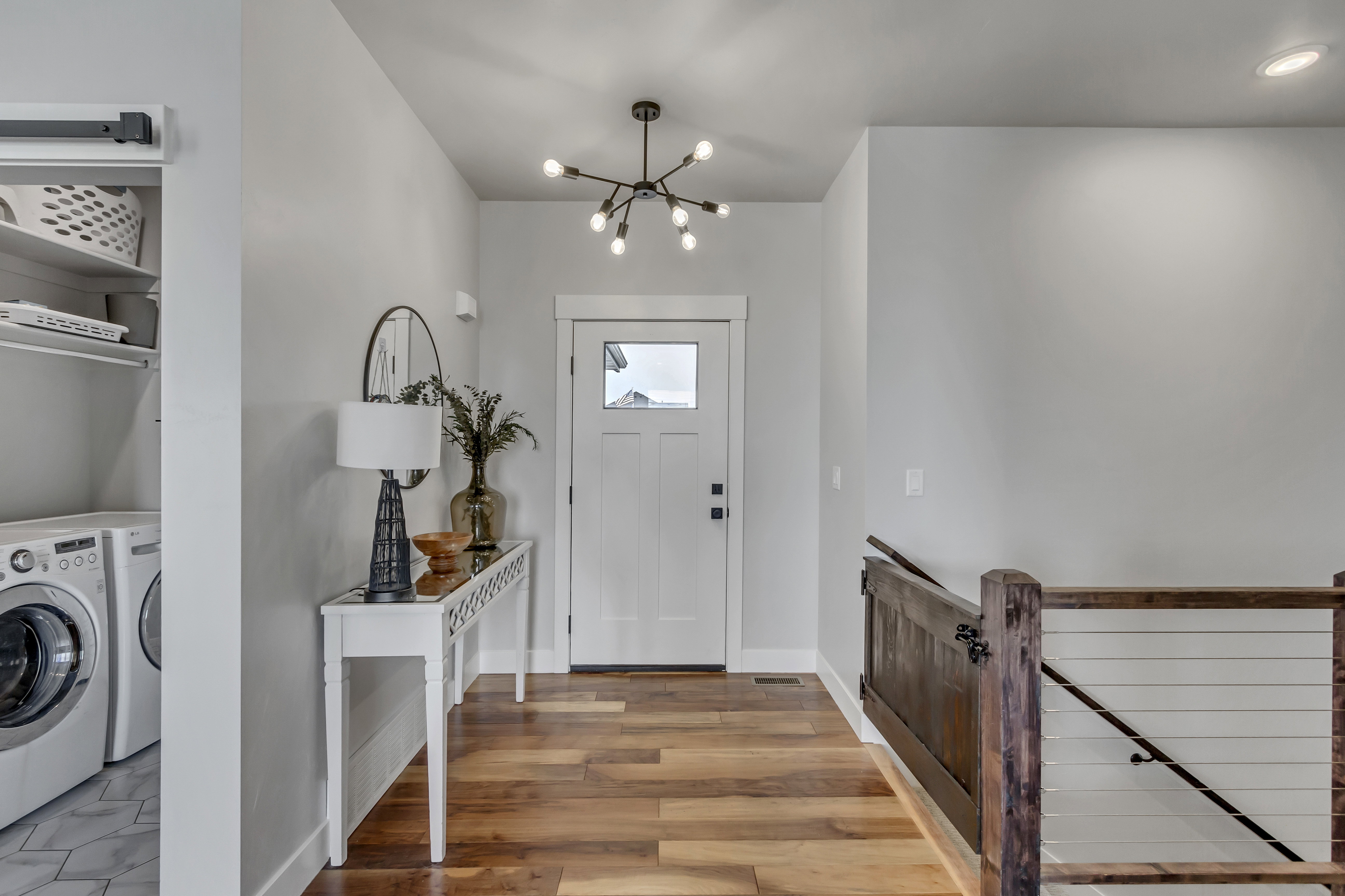 Entryway featuring wood-finish flooring, a white paneled door with a window, and a contemporary chandelier