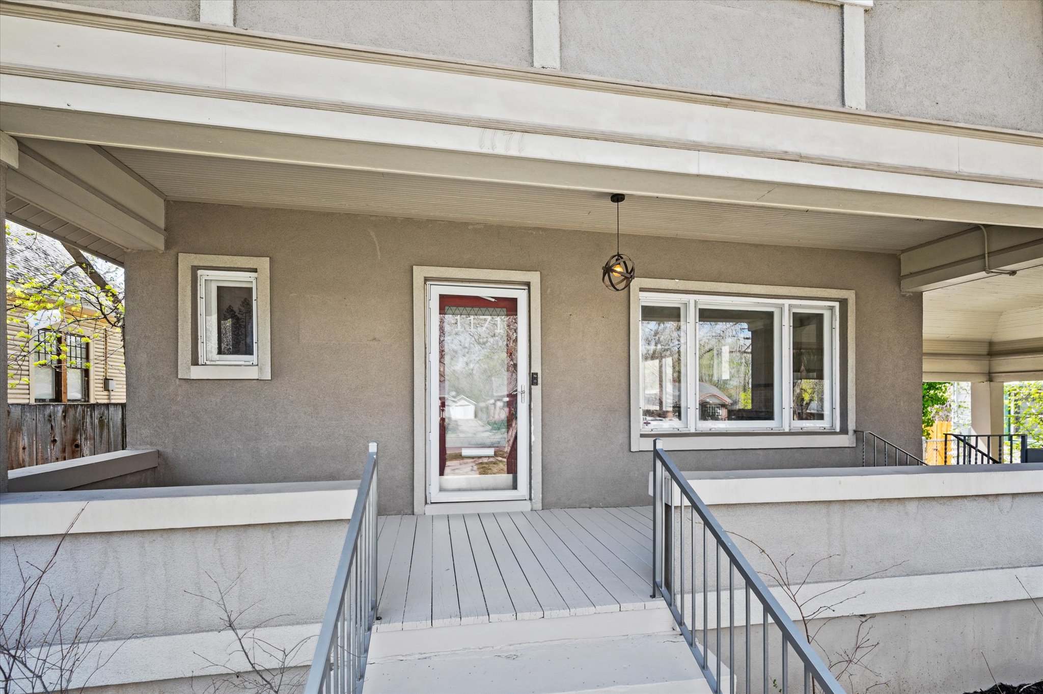Inviting porch with a gray stucco exterior, white trim accents, and a slatted porch floor