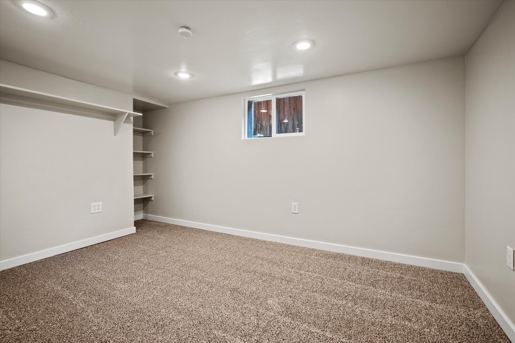 Carpeted room featuring recessed lighting, a window, and built-in shelving