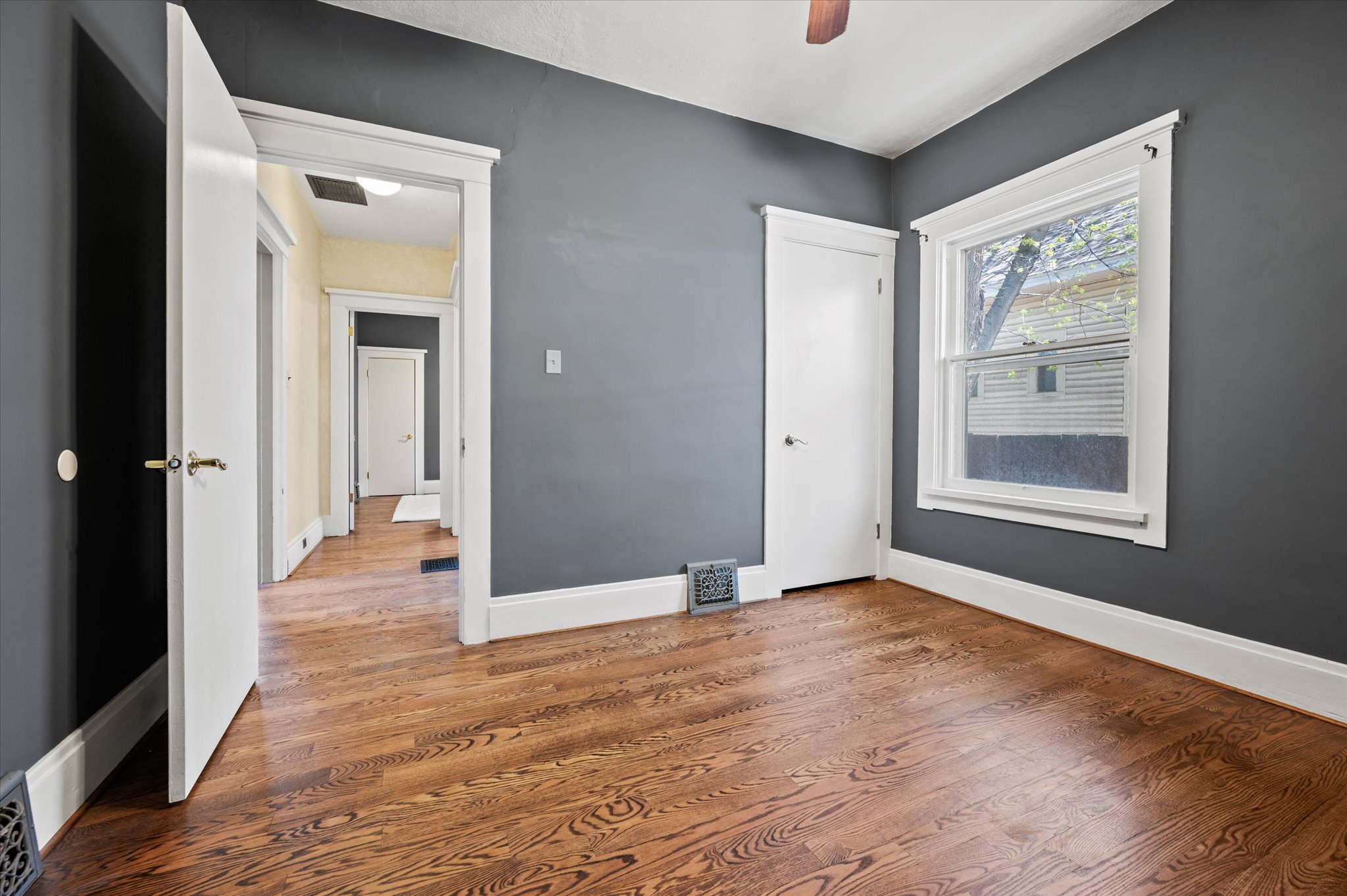 Room featuring wood-finish flooring, dark gray walls, and white trim