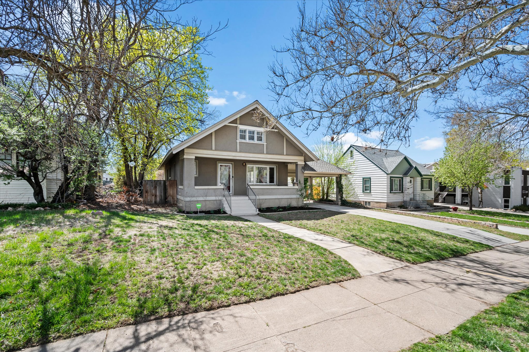 Craftsman-style residence featuring a covered front porch, white trim accents, and a concrete pathway