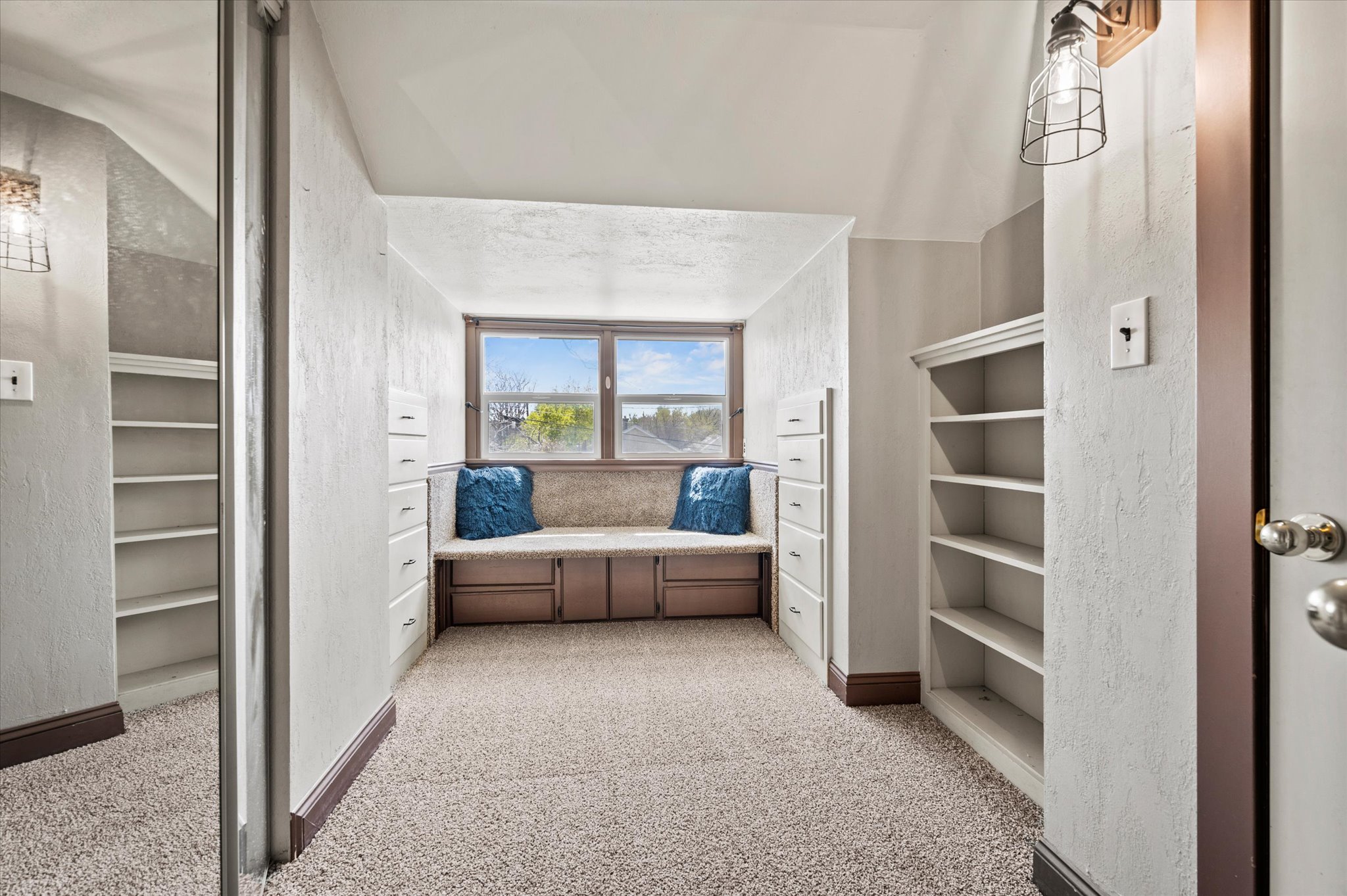 Carpeted room featuring a window seat with built-in storage, built-in shelving, and built-in drawers