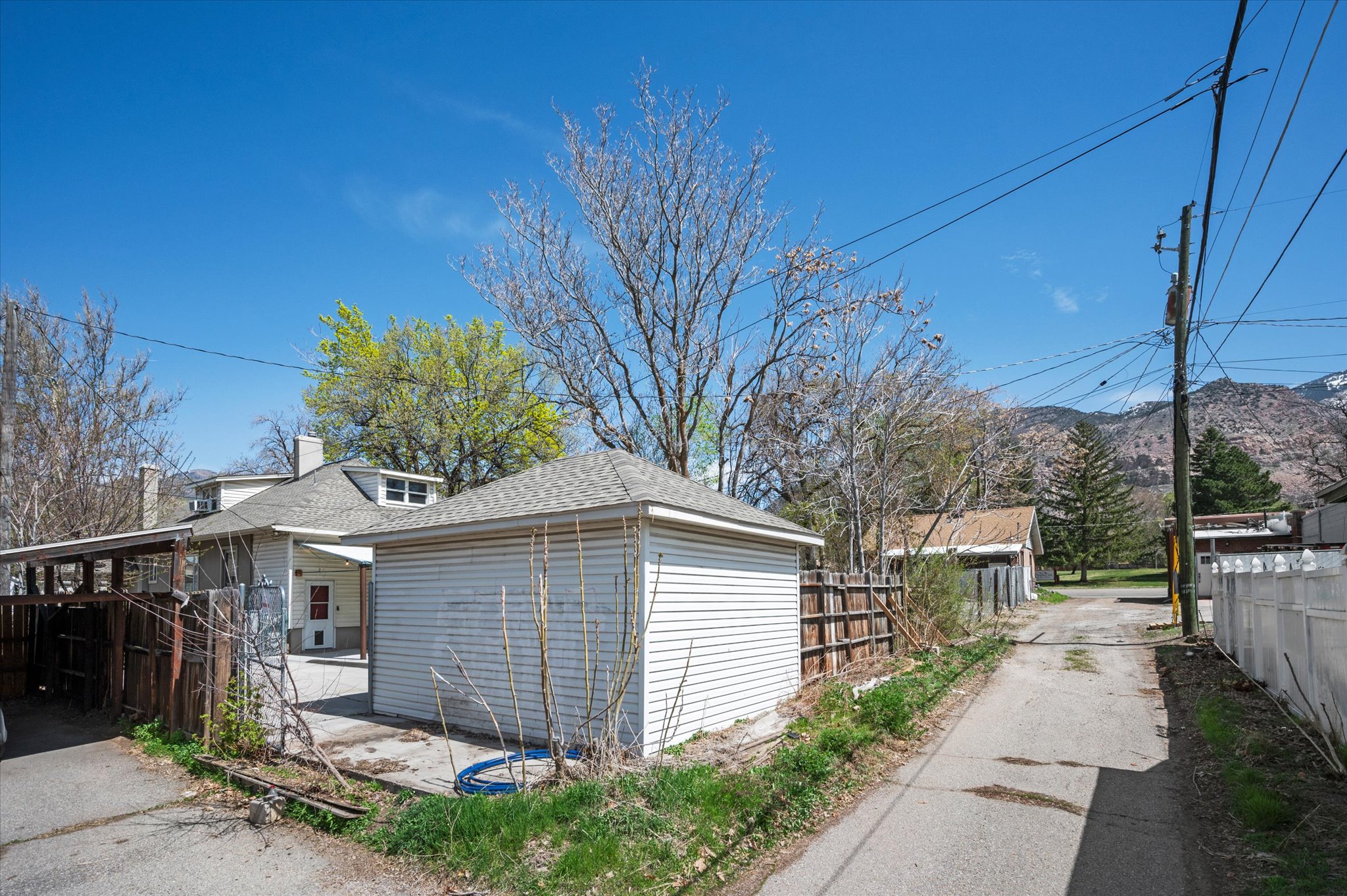 Detached garage with horizontal white siding and a shingled gable roof