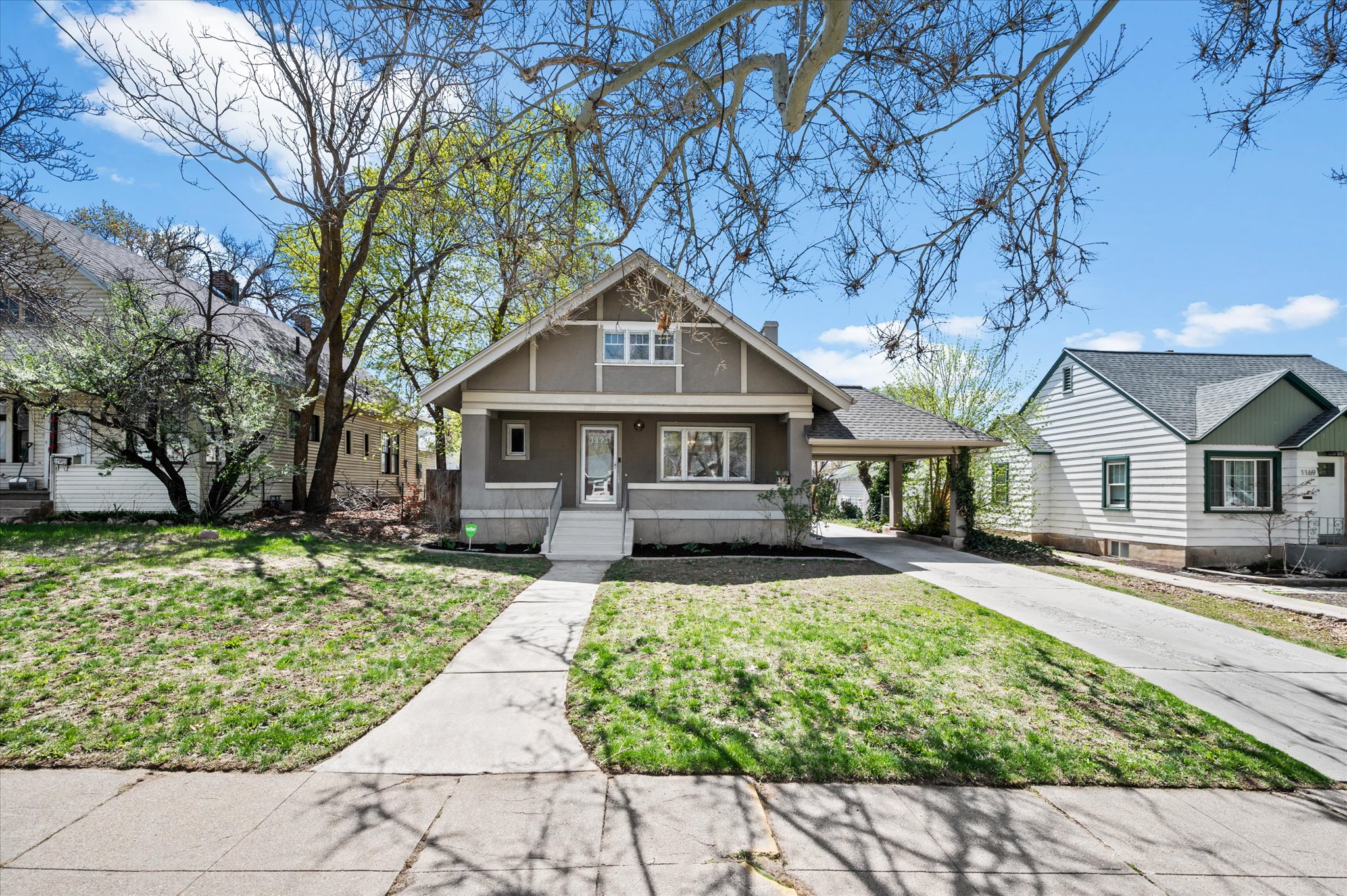Craftsman-style home featuring a covered entry, gabled roofline, front porch steps, an extended driveway, and mature landscaping