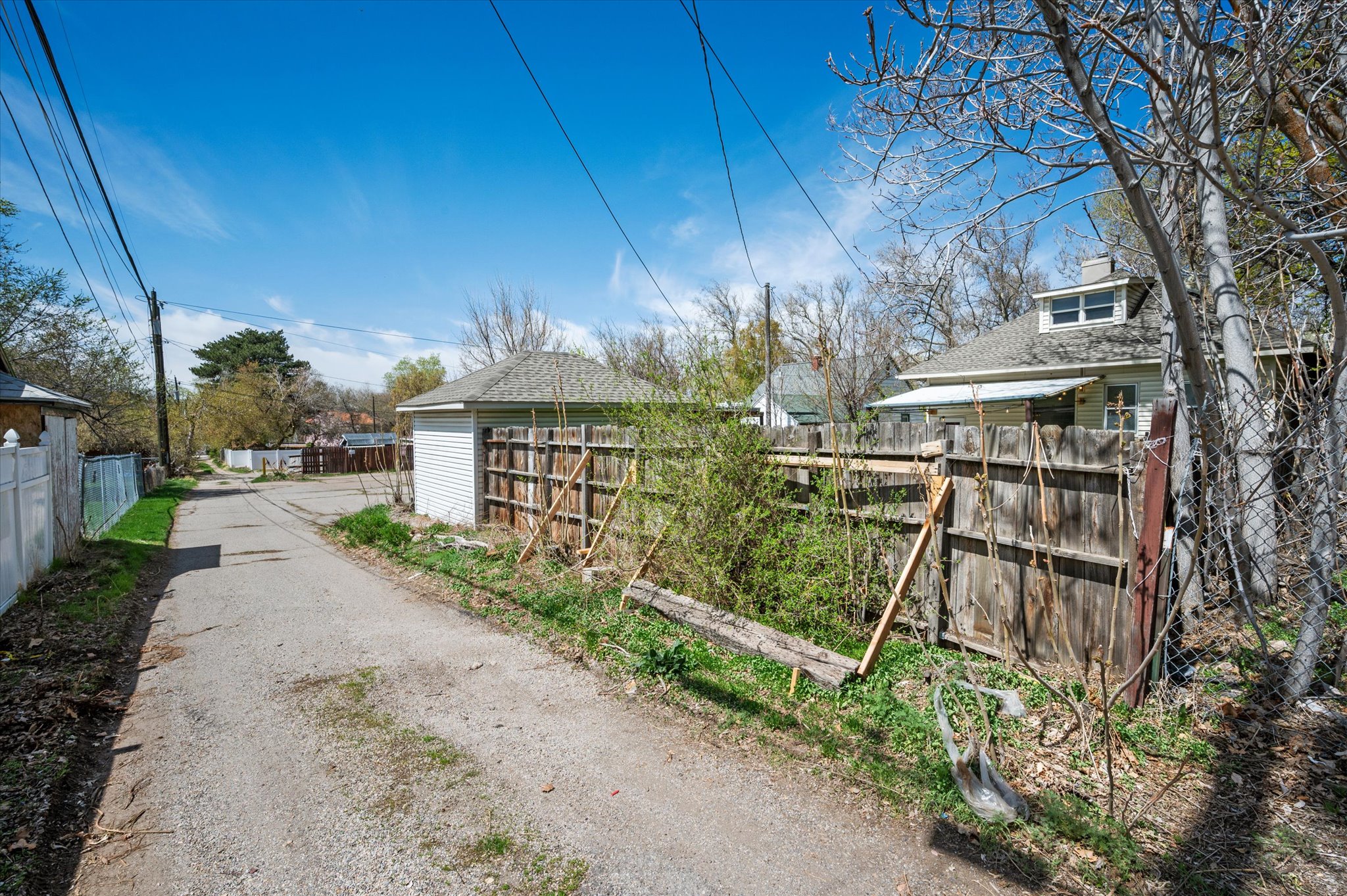 Rear alley access with a detached garage featuring a shingled roof and horizontal siding