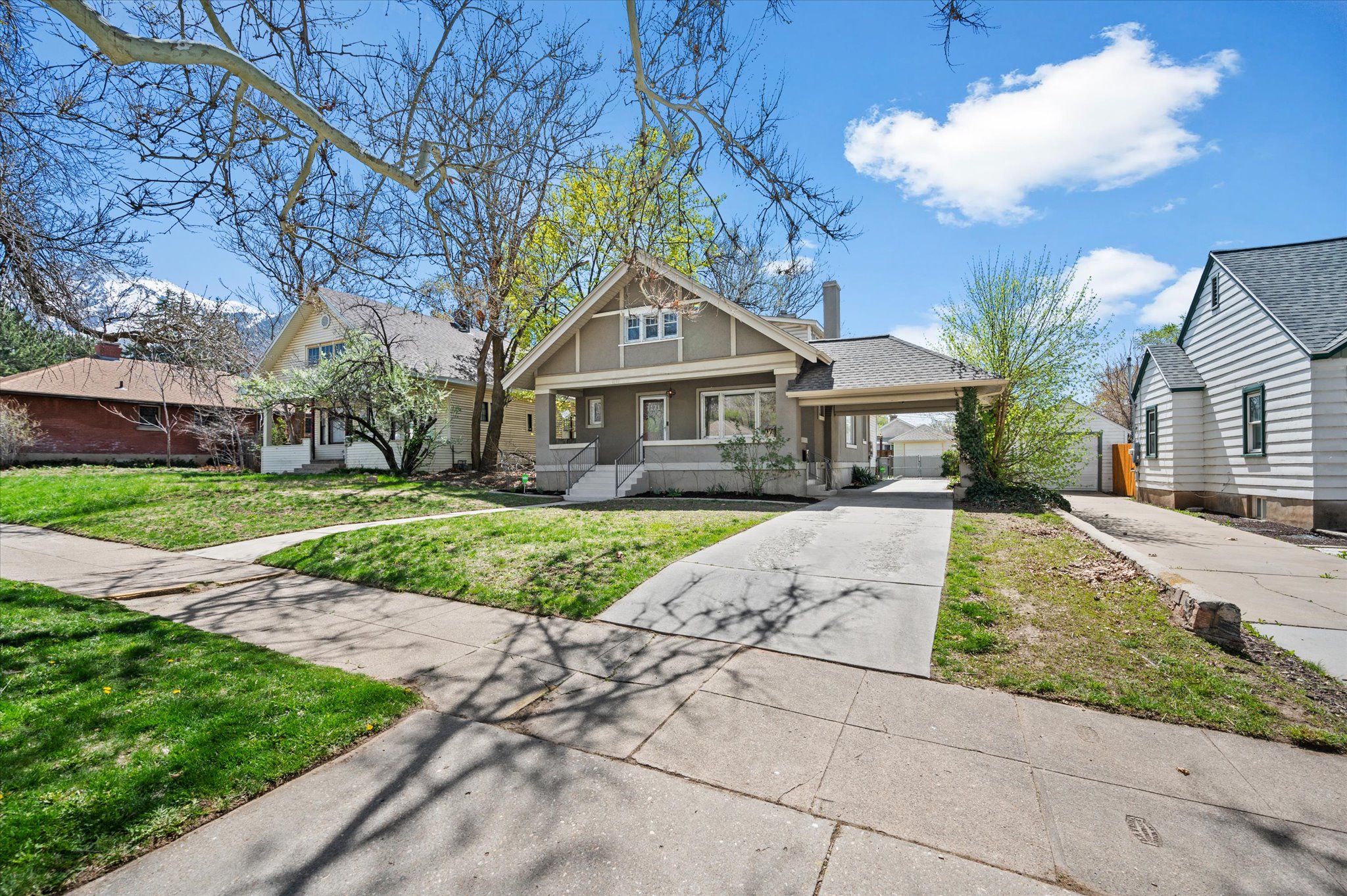 Craftsman-style home featuring a covered carport, pitched roofline, prominent front gable, and a concrete driveway