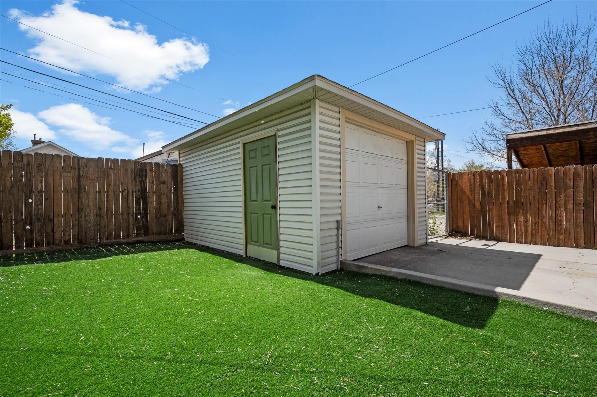 Detached garage featuring white horizontal siding, a light green pedestrian door, and an overhead garage door