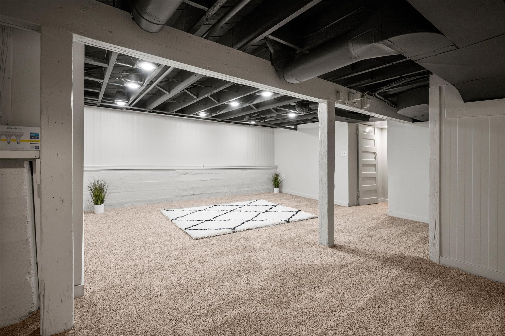 Finished lower level featuring recessed lighting, exposed ceiling joists, neutral carpeting, and painted board and batten paneling