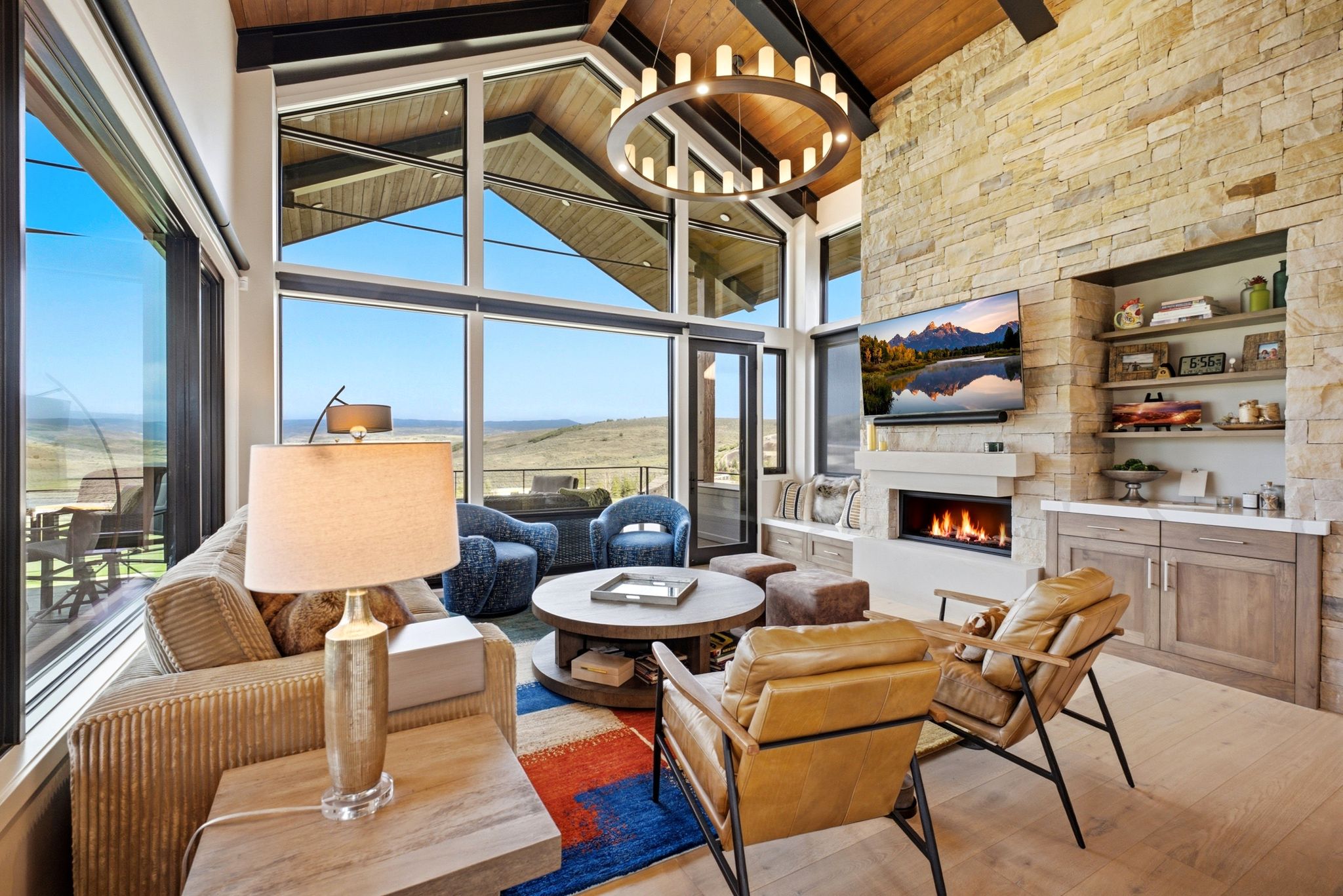 Spacious living area featuring expansive floor-to-ceiling windows, a stone accent wall, and a linear fireplace