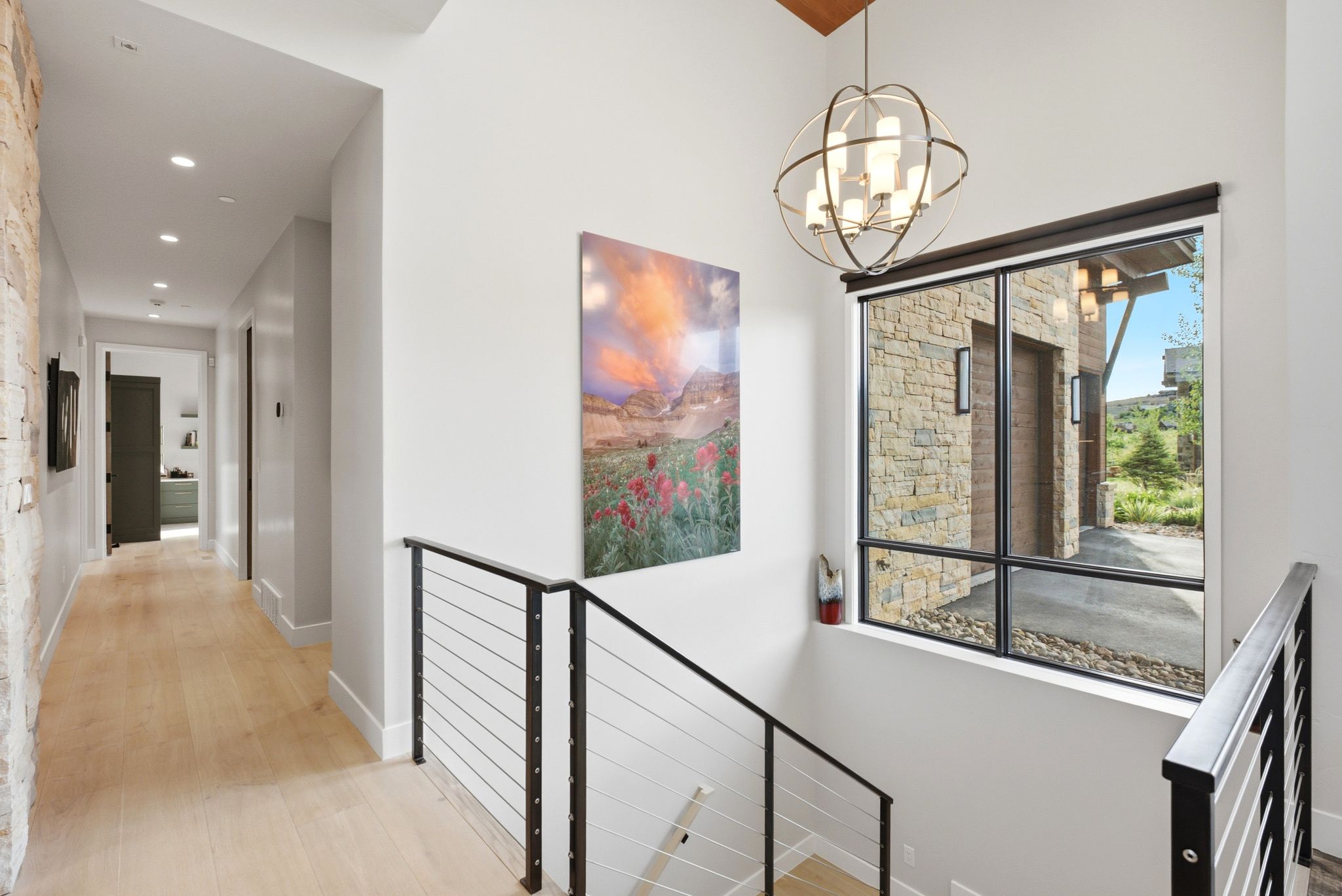 Stairwell with iron railing and cable infill, featuring a large window with exterior stone accents