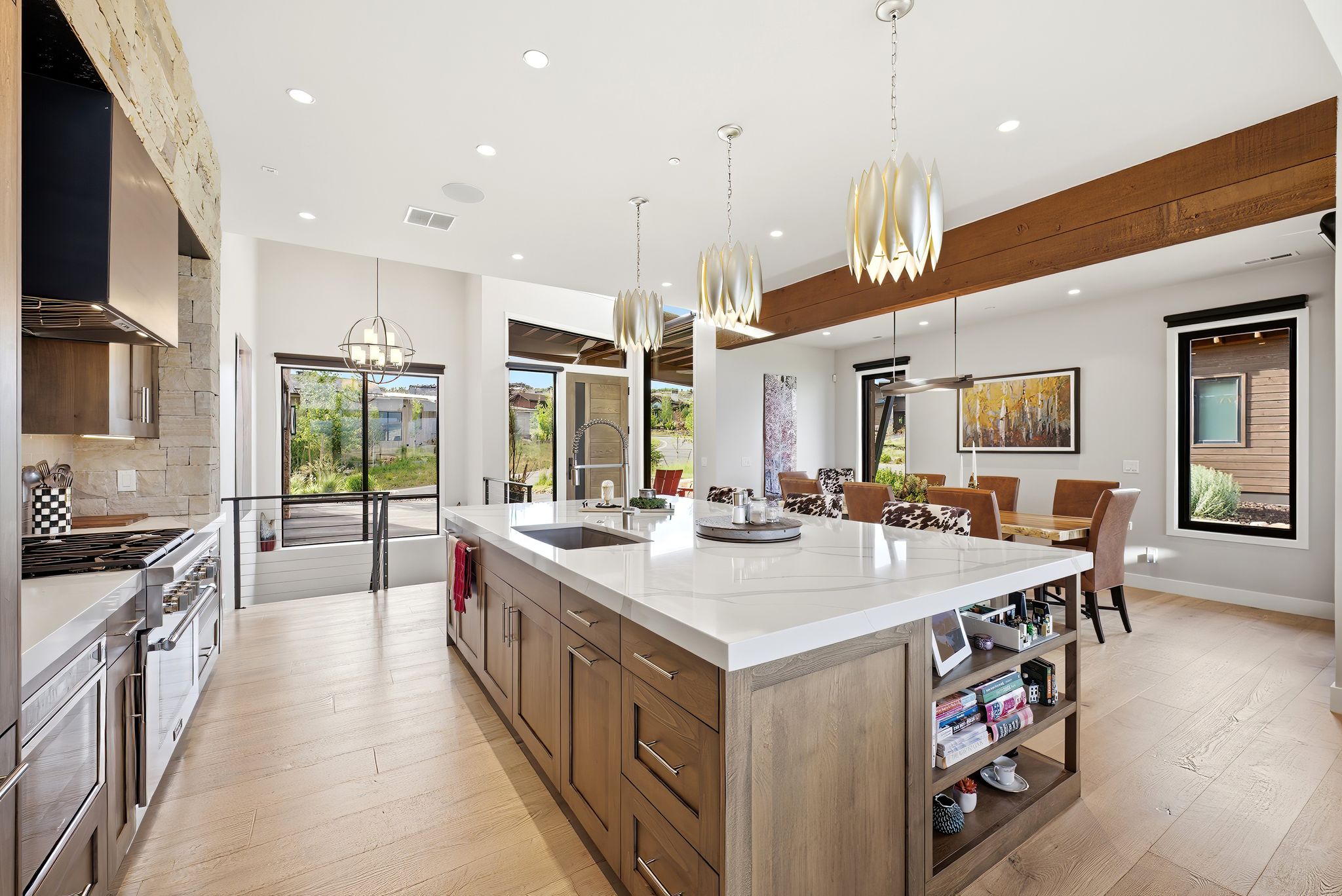 Gourmet kitchen featuring a large central island with a built-in sink, white stone-finish countertop, and integrated shelving