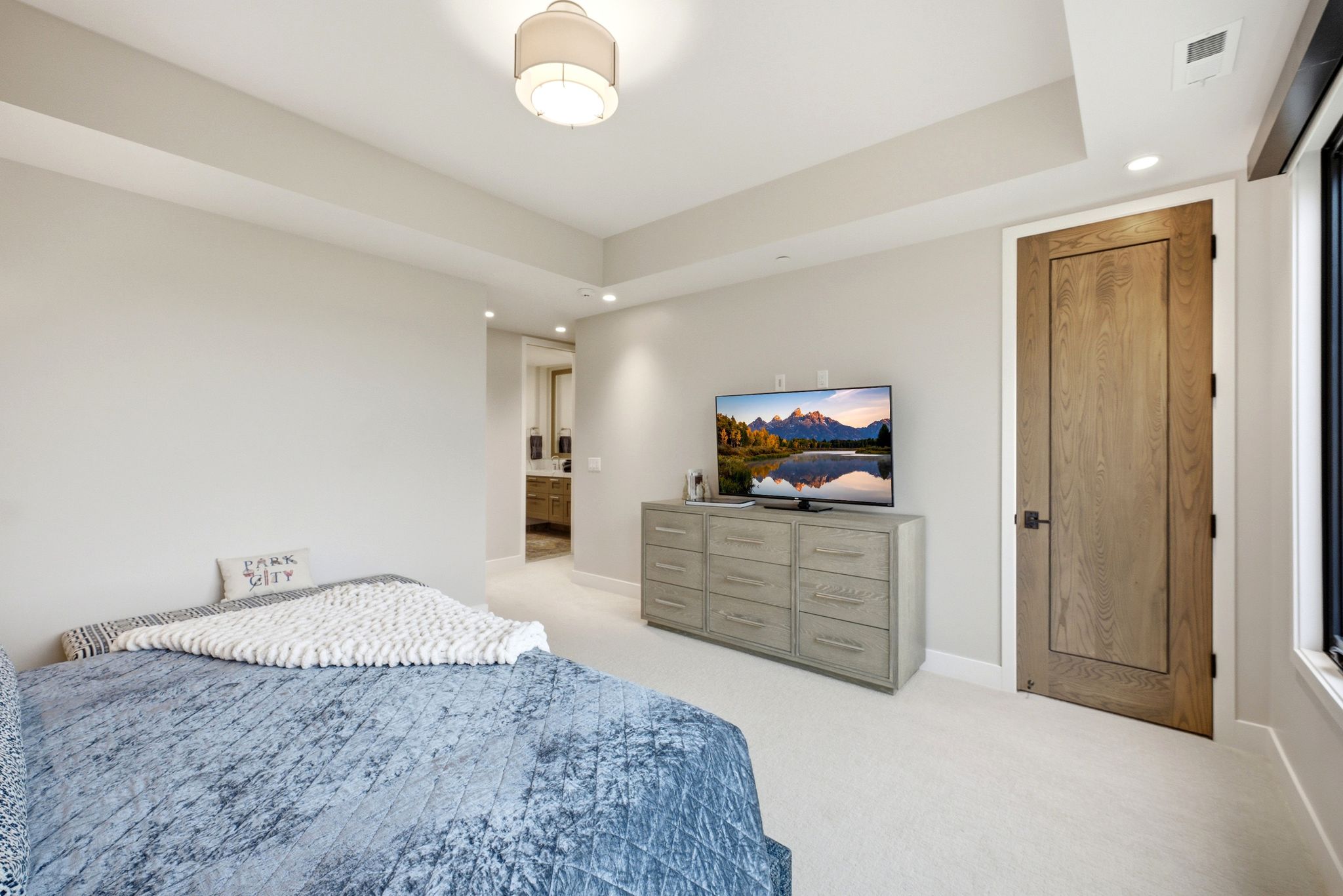 Recessed lighting illuminates a space featuring light-toned walls and plush carpeting
