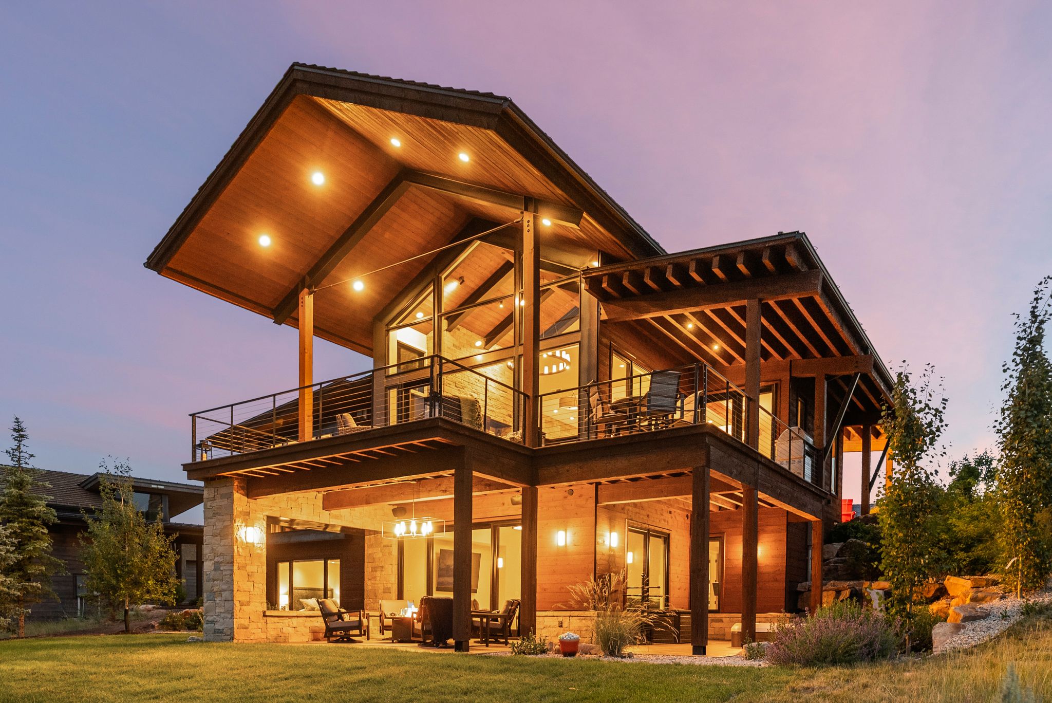 Expansive two-story home featuring a stone and wood exterior with multiple outdoor living areas