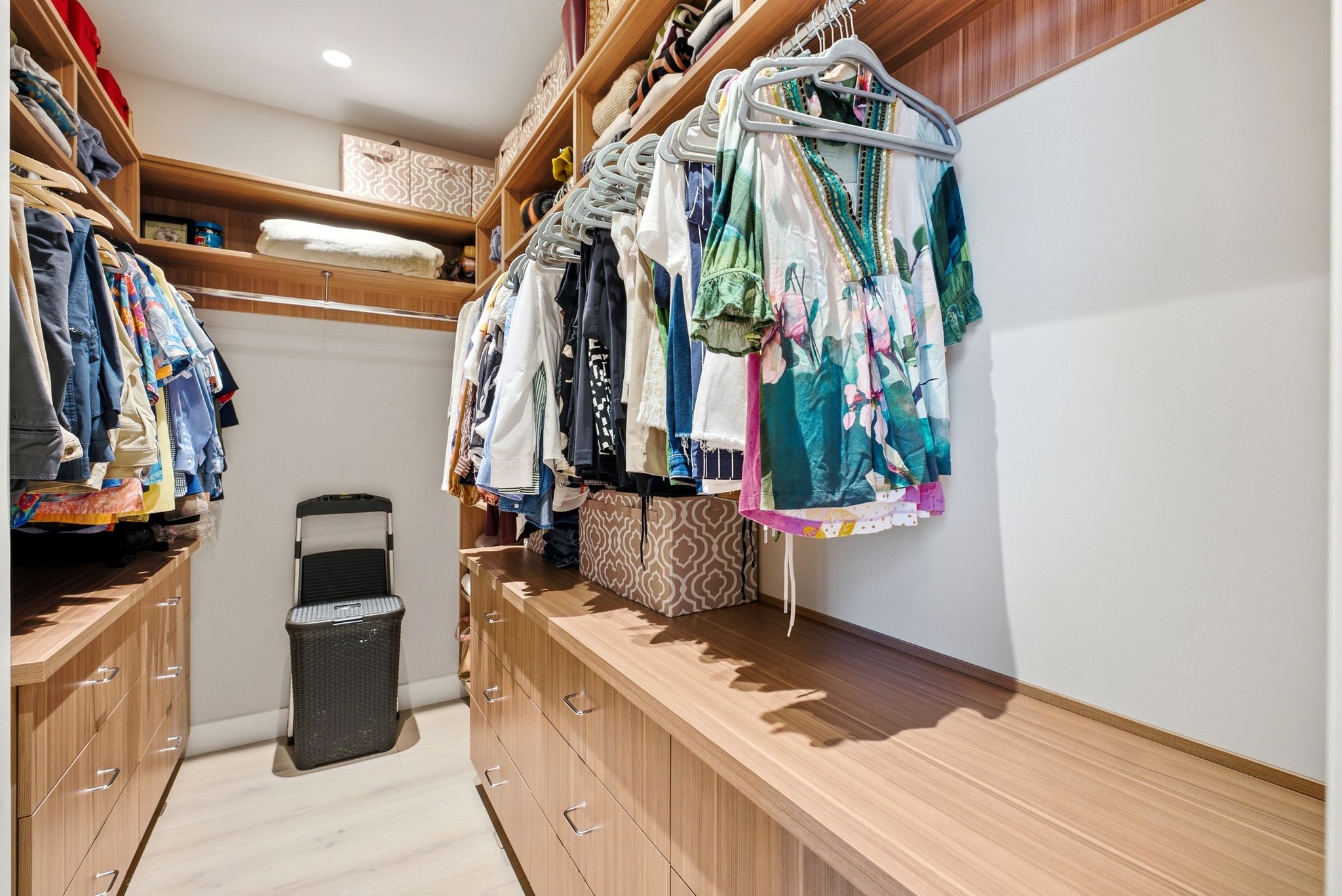 Walk-in closet featuring extensive built-in wood-finish cabinetry, integrated shelving, ample hanging storage, and recessed lighting