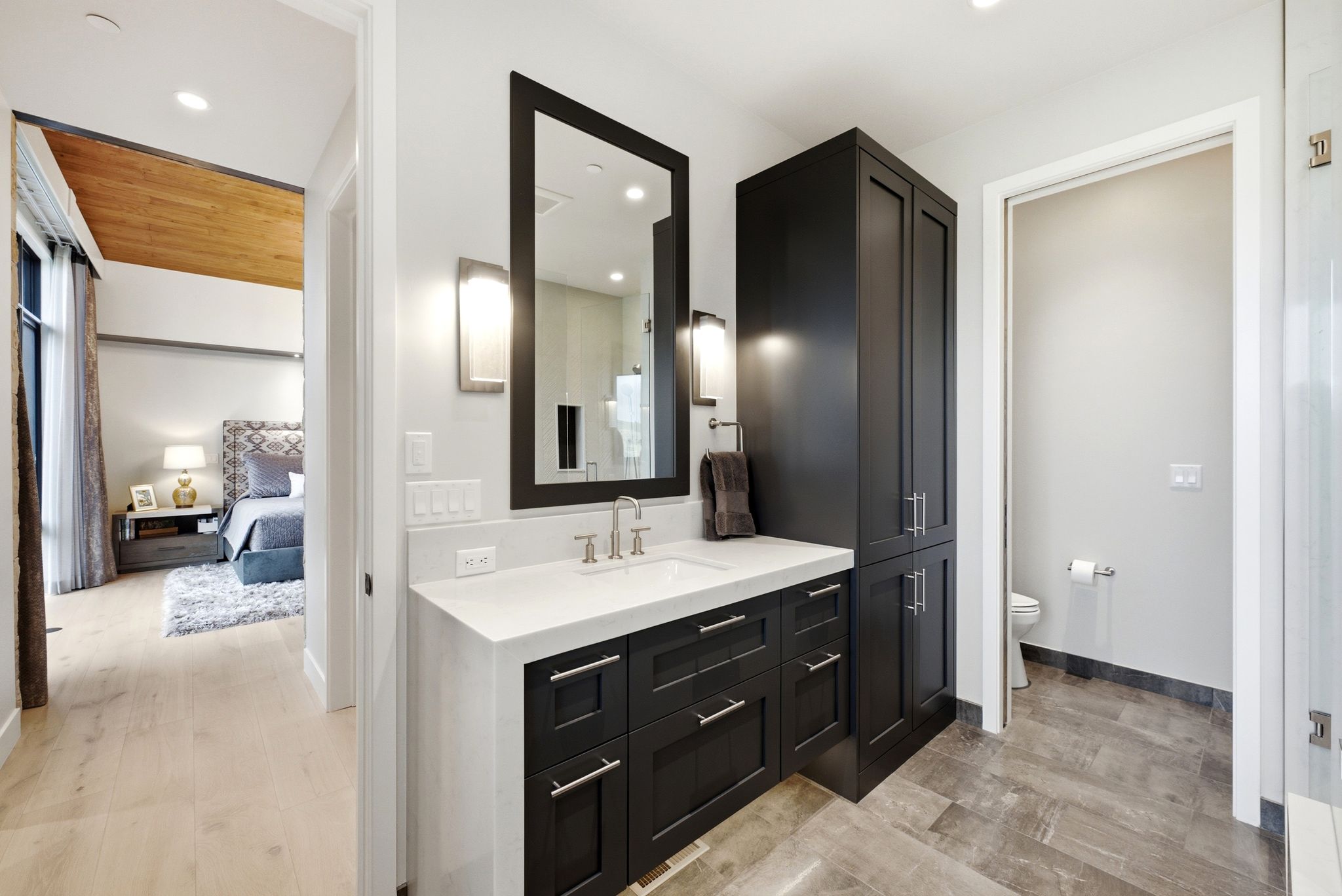 Bathroom vanity featuring a single basin, dark cabinetry, and white countertop