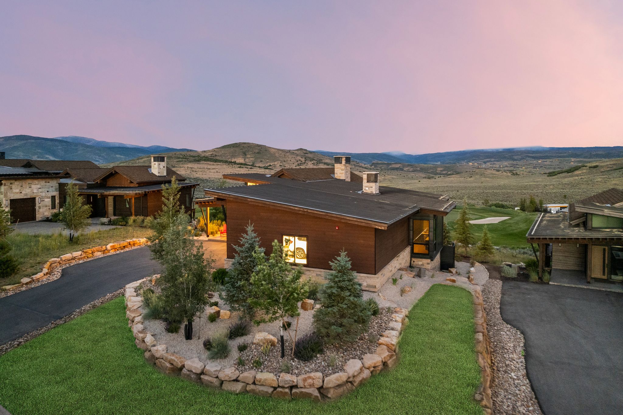 Modern architectural residence featuring multiple structures with dark wood-finish siding and stone accents