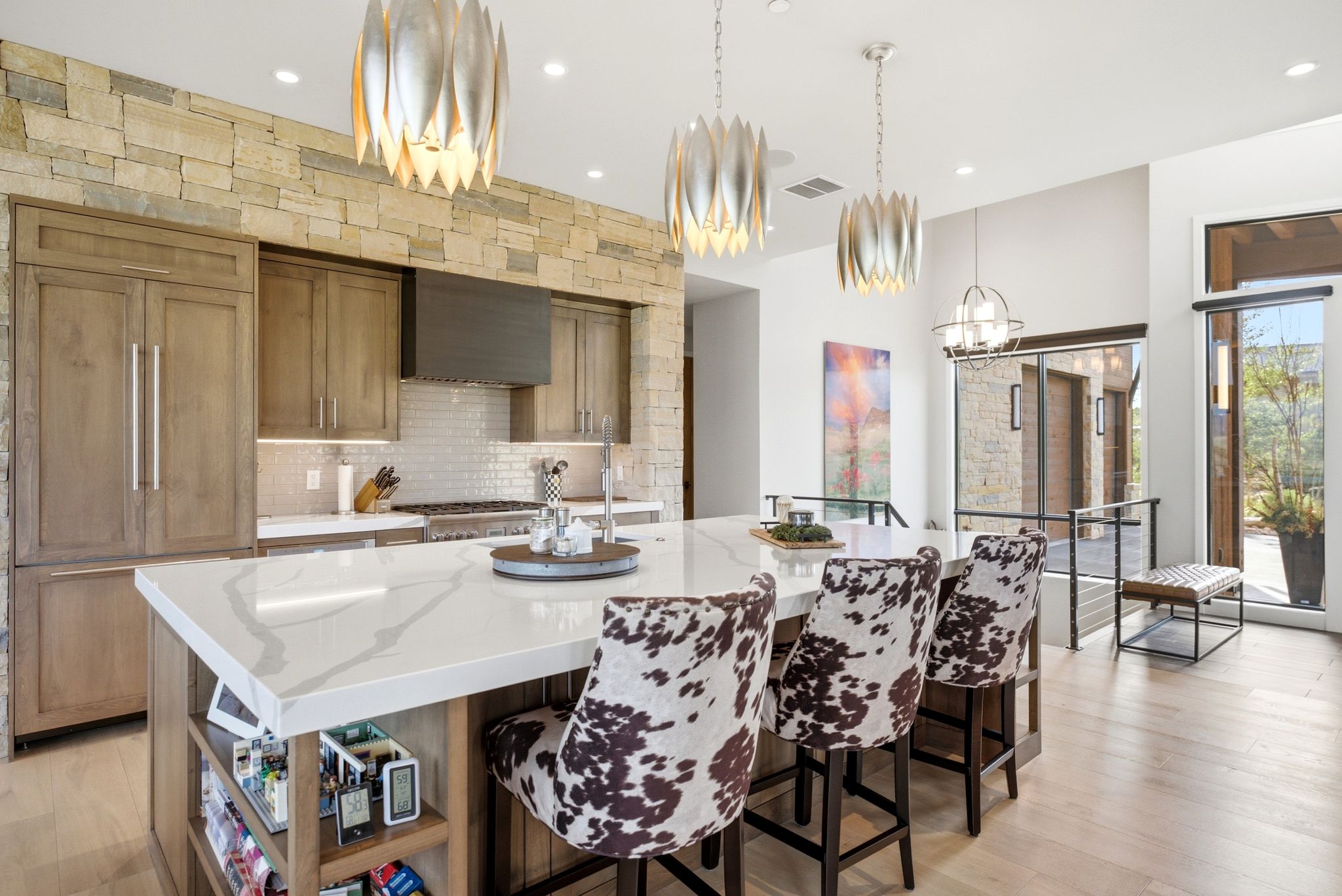Kitchen featuring a large central island with a light-toned countertop, integrated shelving, and three pendant light fixtures