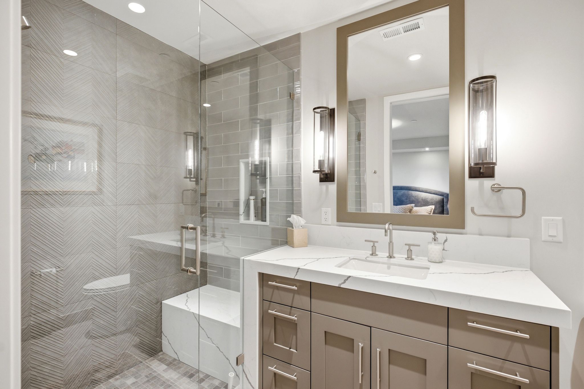 Glass-enclosed shower with a built-in bench and herringbone-patterned wall tile