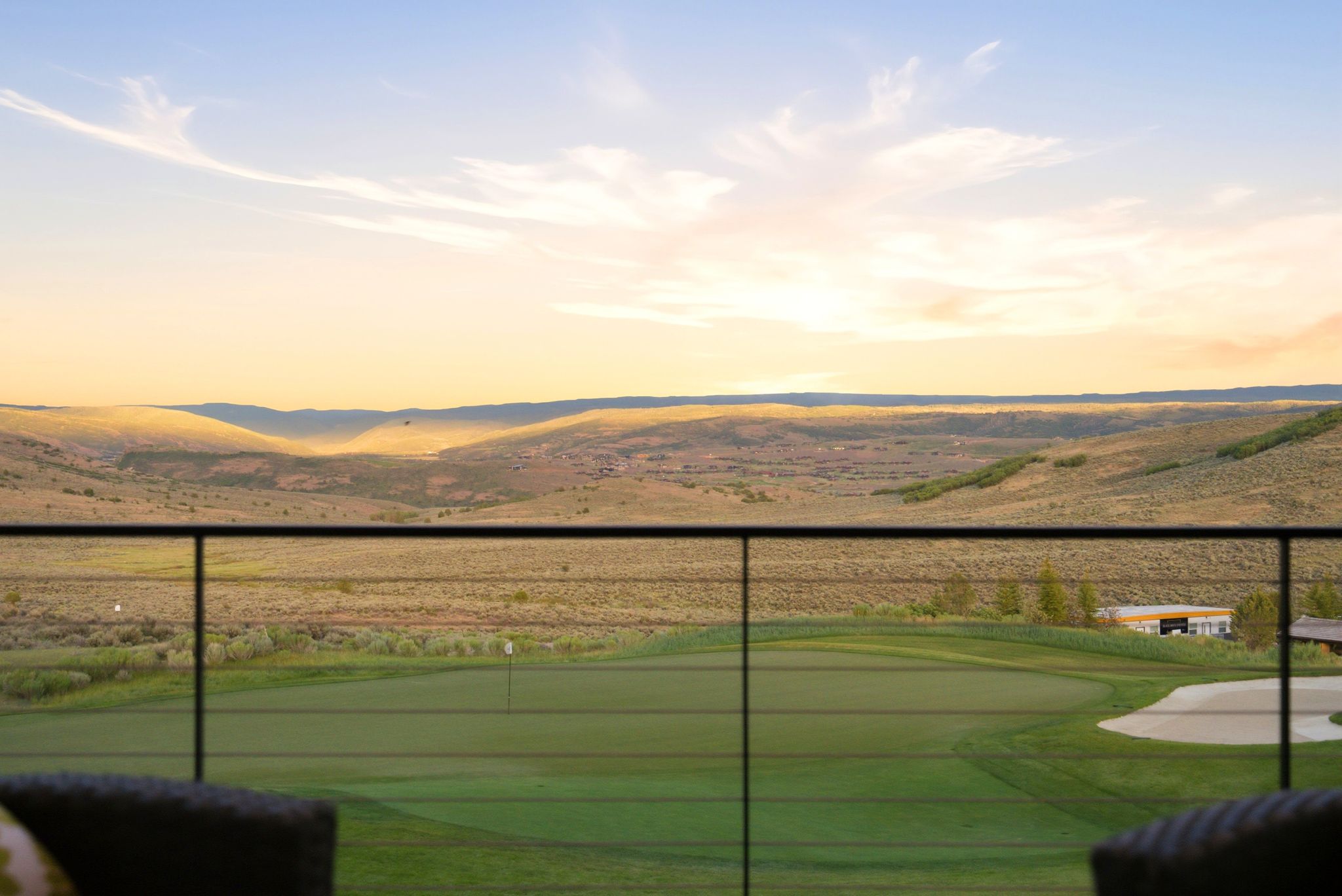 Outdoor living area with a cable railing system offering expansive golf course and distant hillside scenery