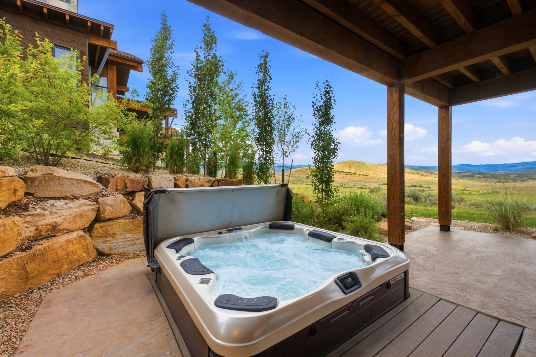Outdoor hot tub on a concrete patio with a wooden overhead structure