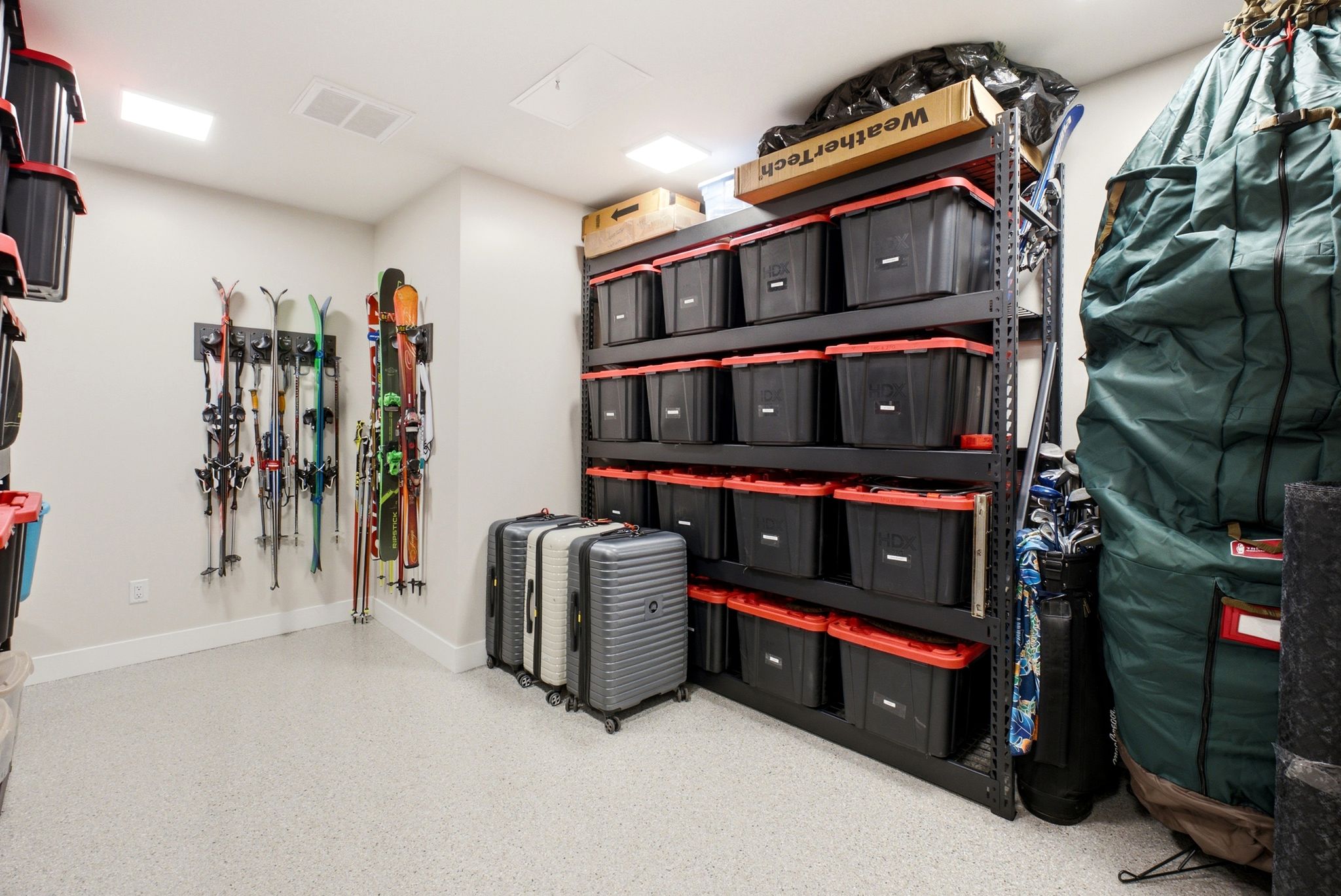 Dedicated storage space featuring light-colored flooring, wall-mounted ski racks, and industrial-style shelving