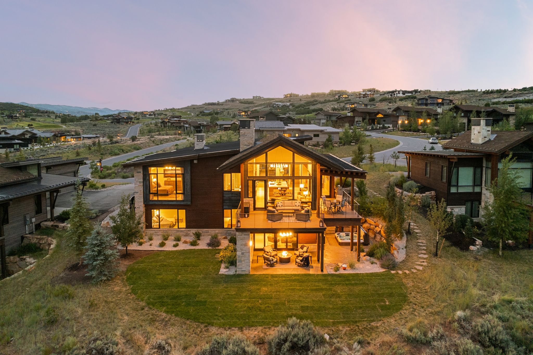 Contemporary mountain-style residence featuring extensive glazing, a stone and wood siding exterior, and multiple outdoor entertaining areas