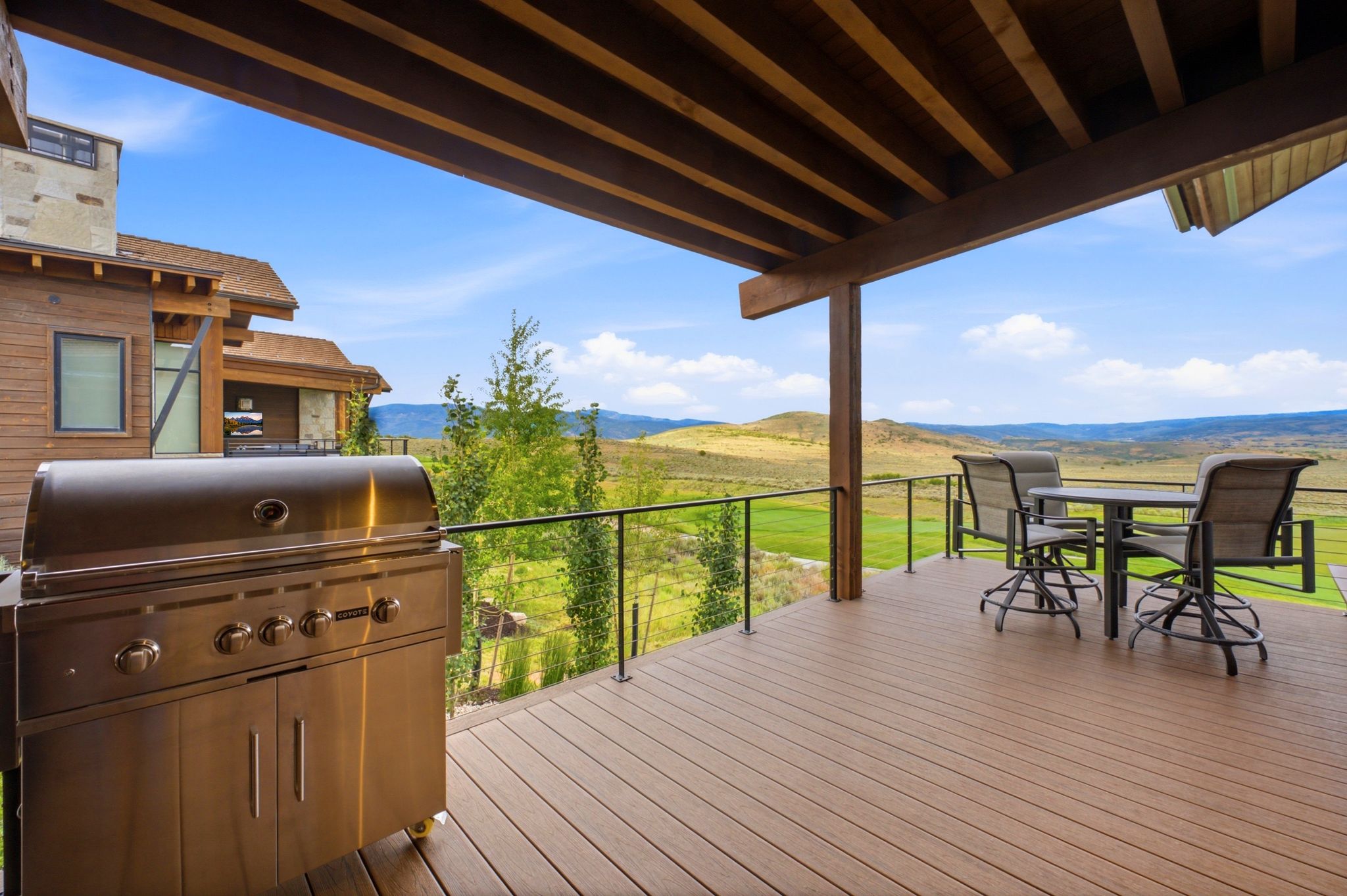 Expansive outdoor deck featuring wood-finish flooring and a partial overhead wooden beam structure