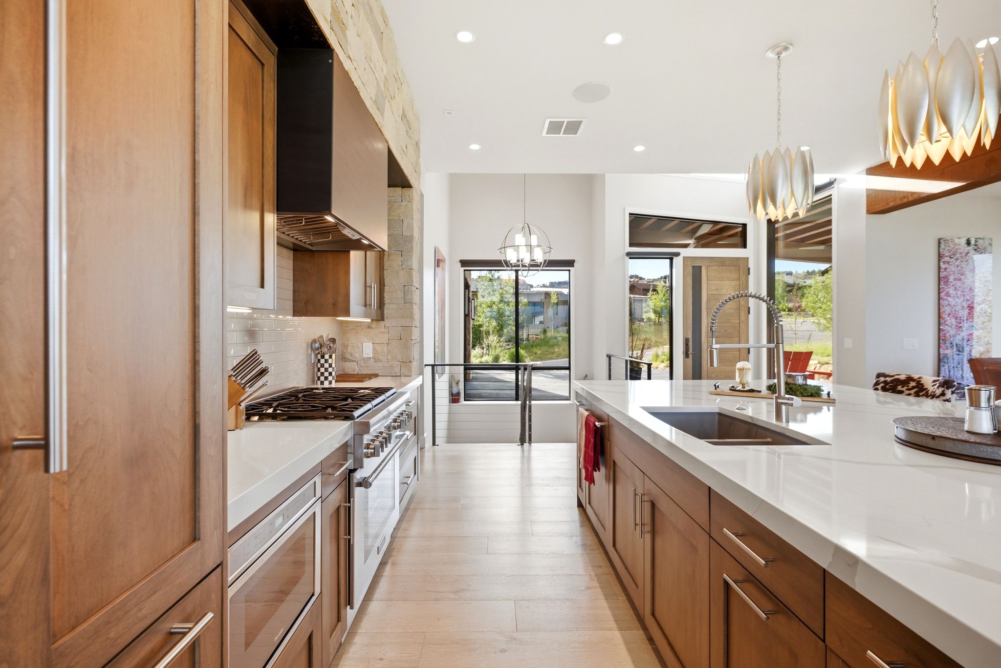 Modern kitchen featuring wood-finish cabinetry, light-toned countertops, and stainless steel appliances