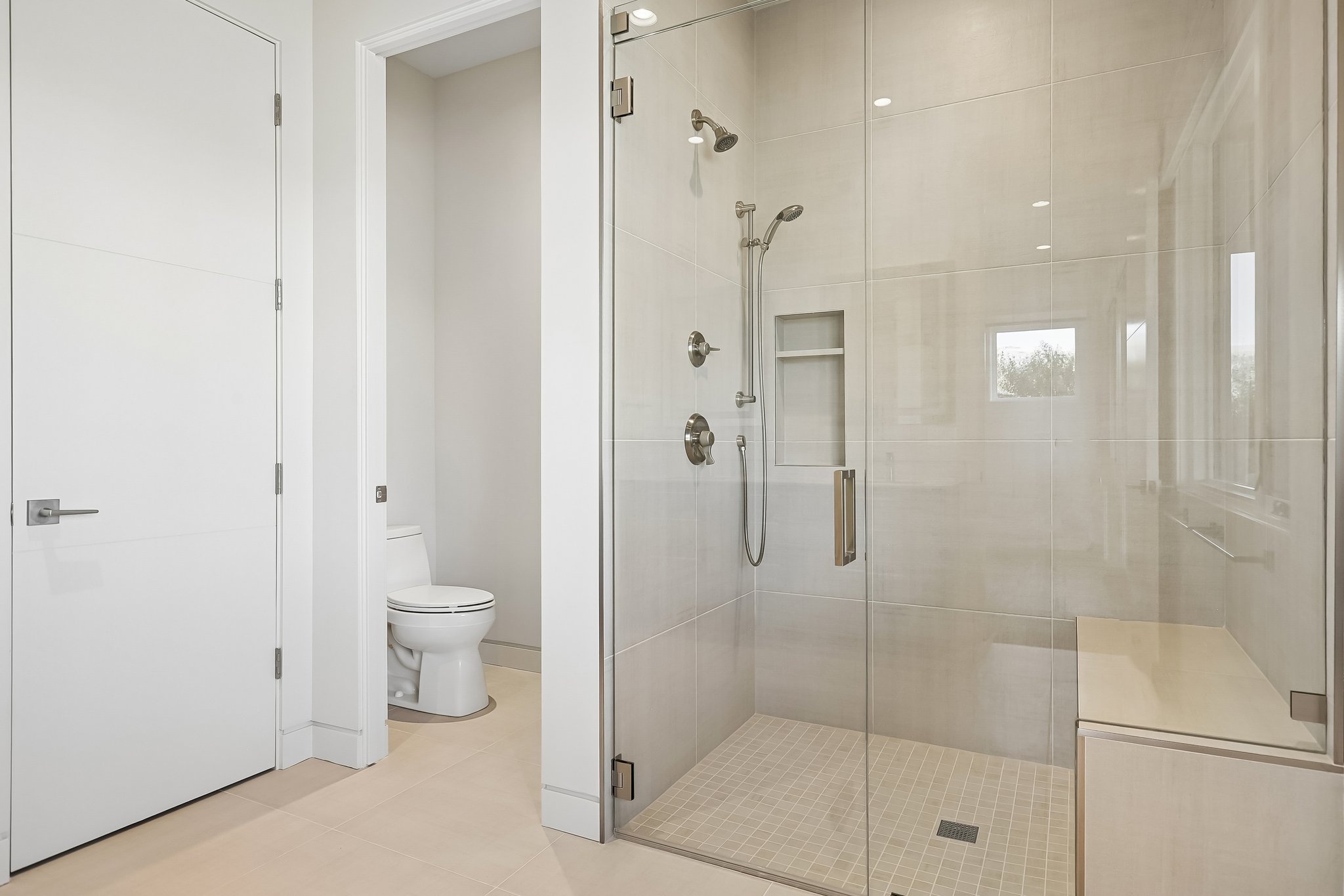 Spacious walk-in shower with clear glass enclosure and a built-in bench