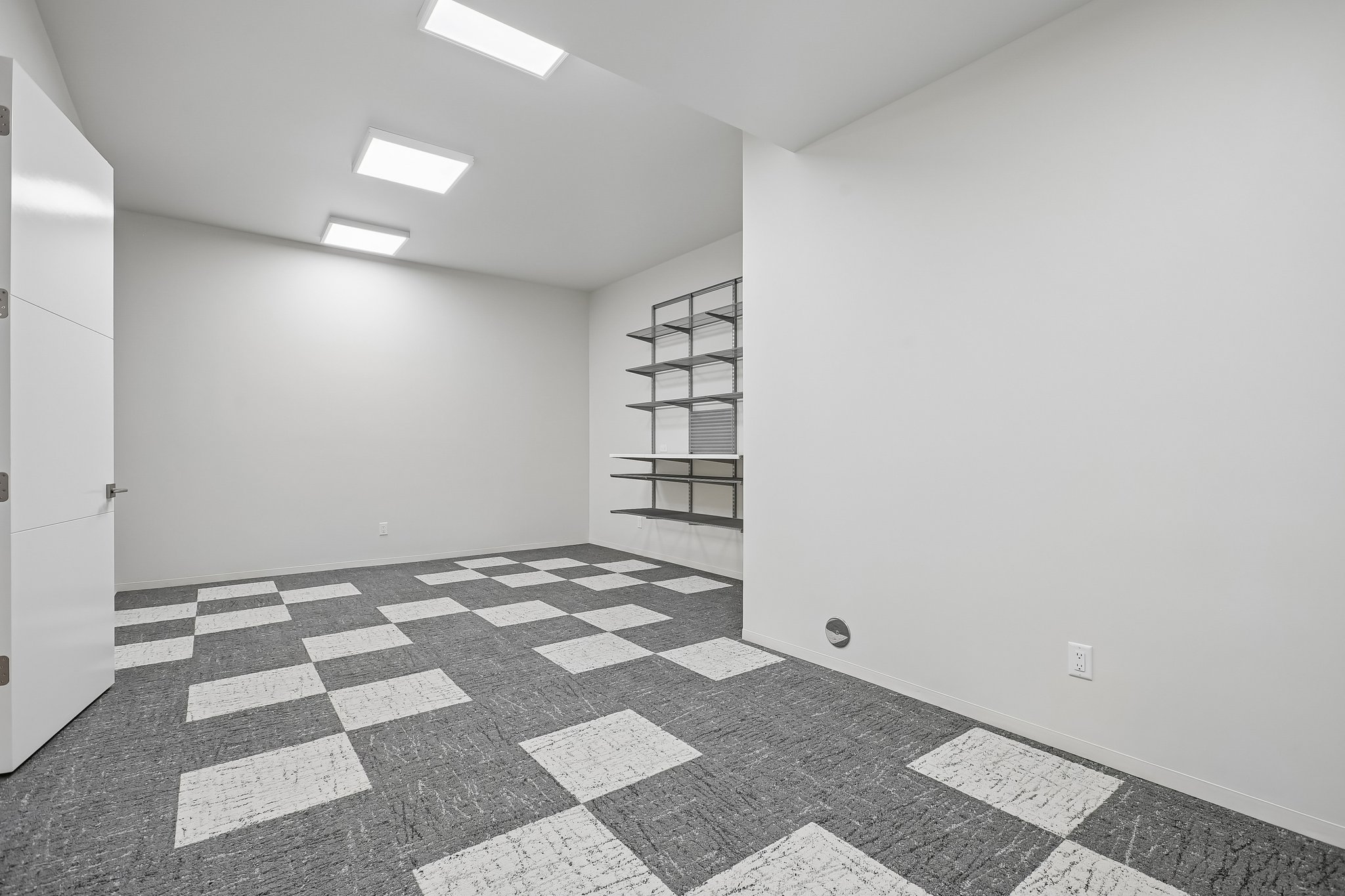 Spacious room featuring patterned carpet flooring, extensive built-in shelving, and contemporary recessed lighting